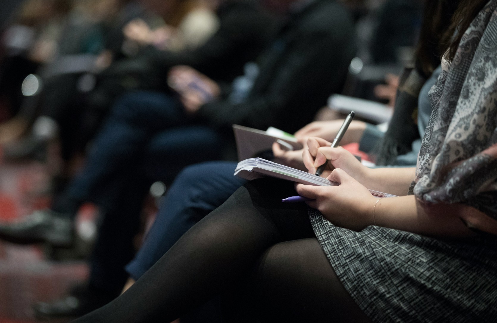 Audience members taking notes during a conference.