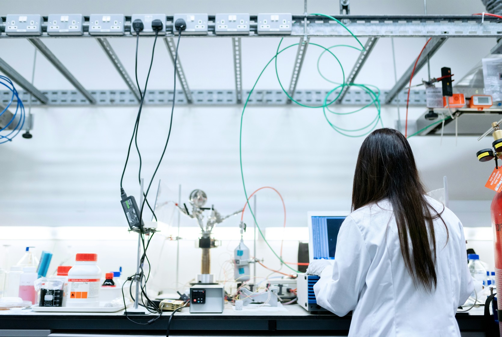 Researcher working in a laboratory with equipment and cables.