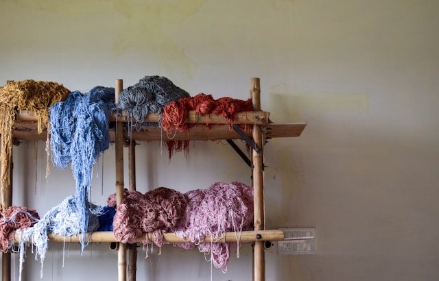 Bunches of colorful yarn on a wooden shelf.