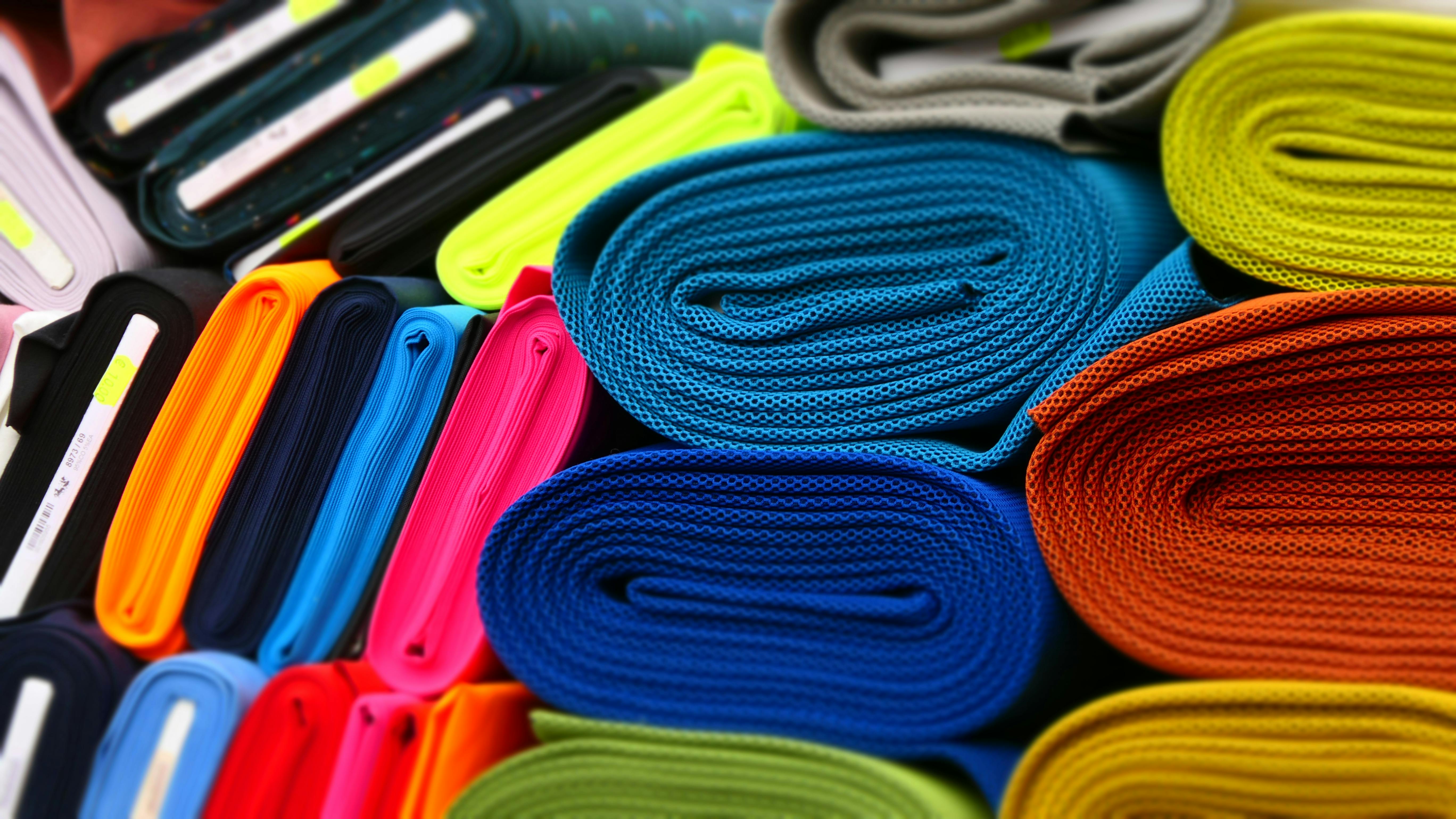 Colourful fabrics neatly rolled and displayed in a textile store.