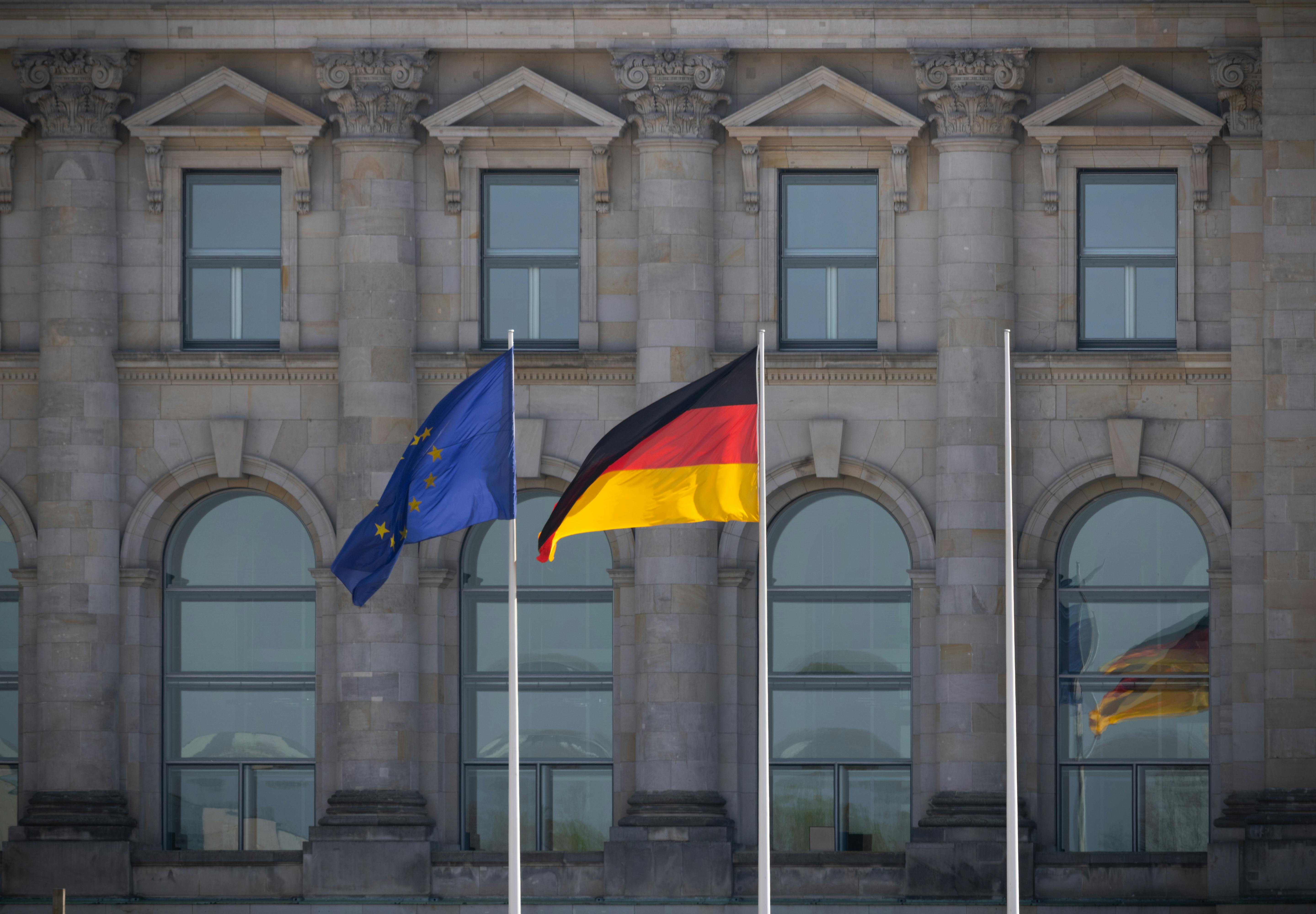 German and EU flags flying in front of the Reichstag building in Berlin, Germany.