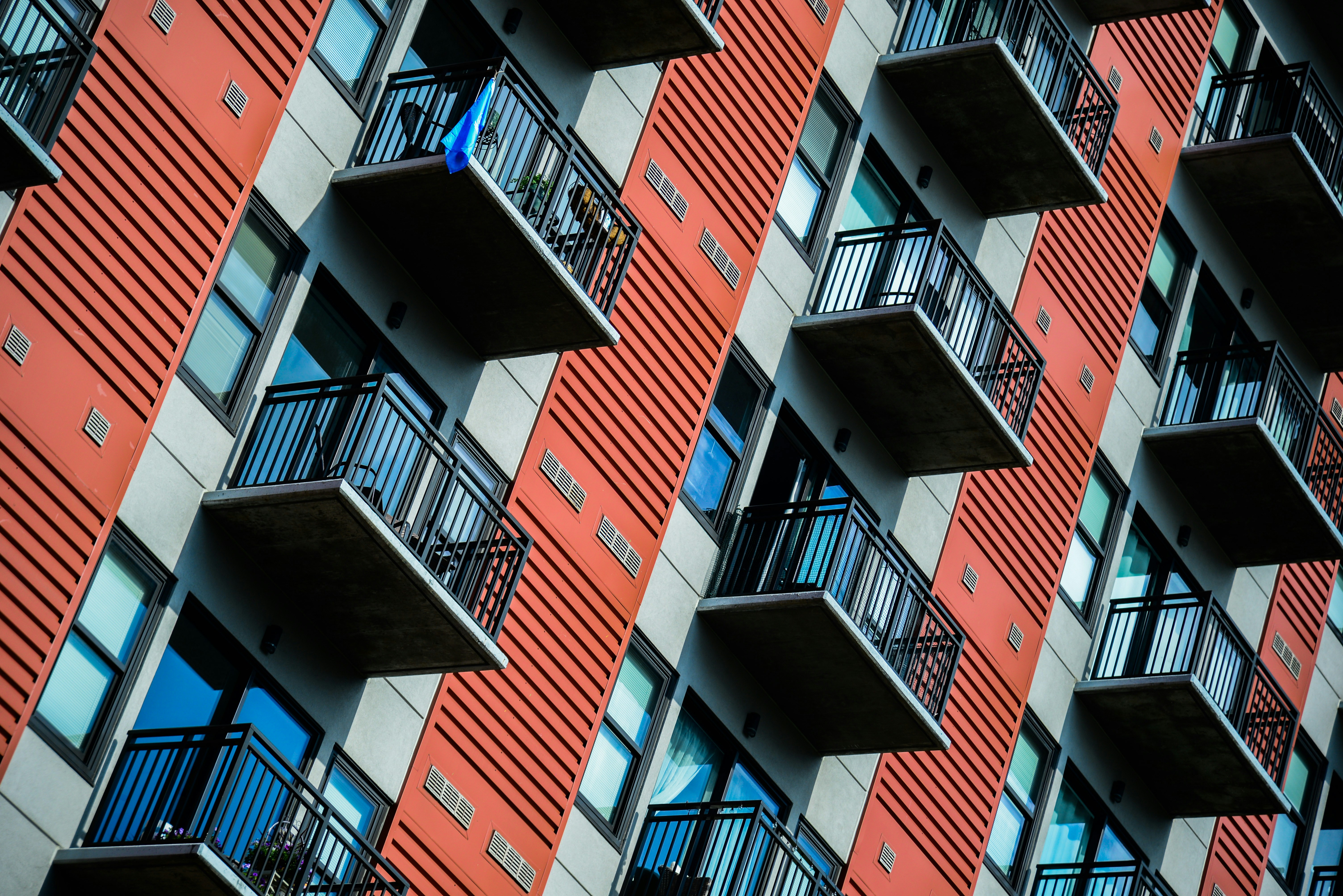 The image shows the exterior of a modern apartment building with multiple balconies.