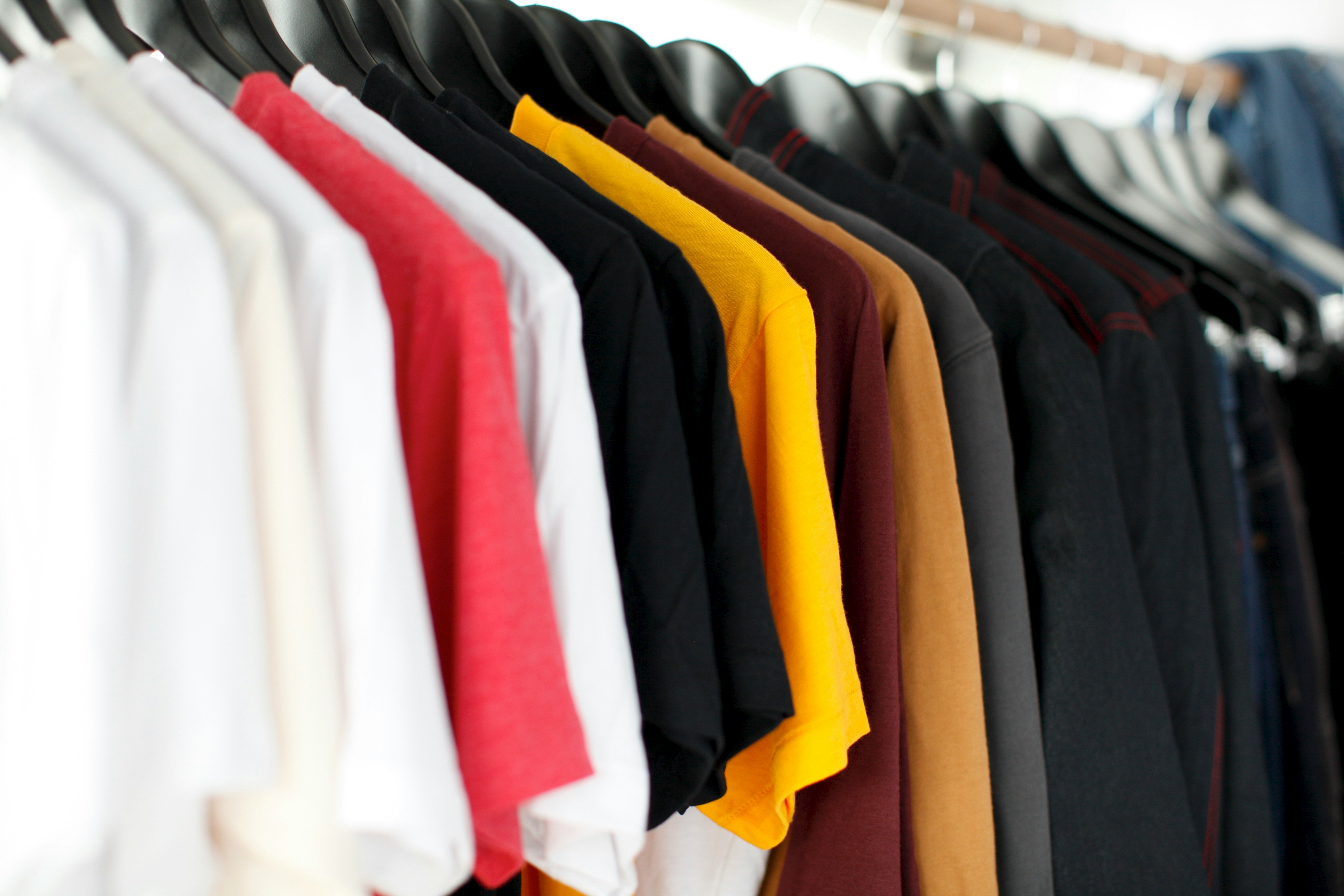 Clothes in various colors hanging on a rack.