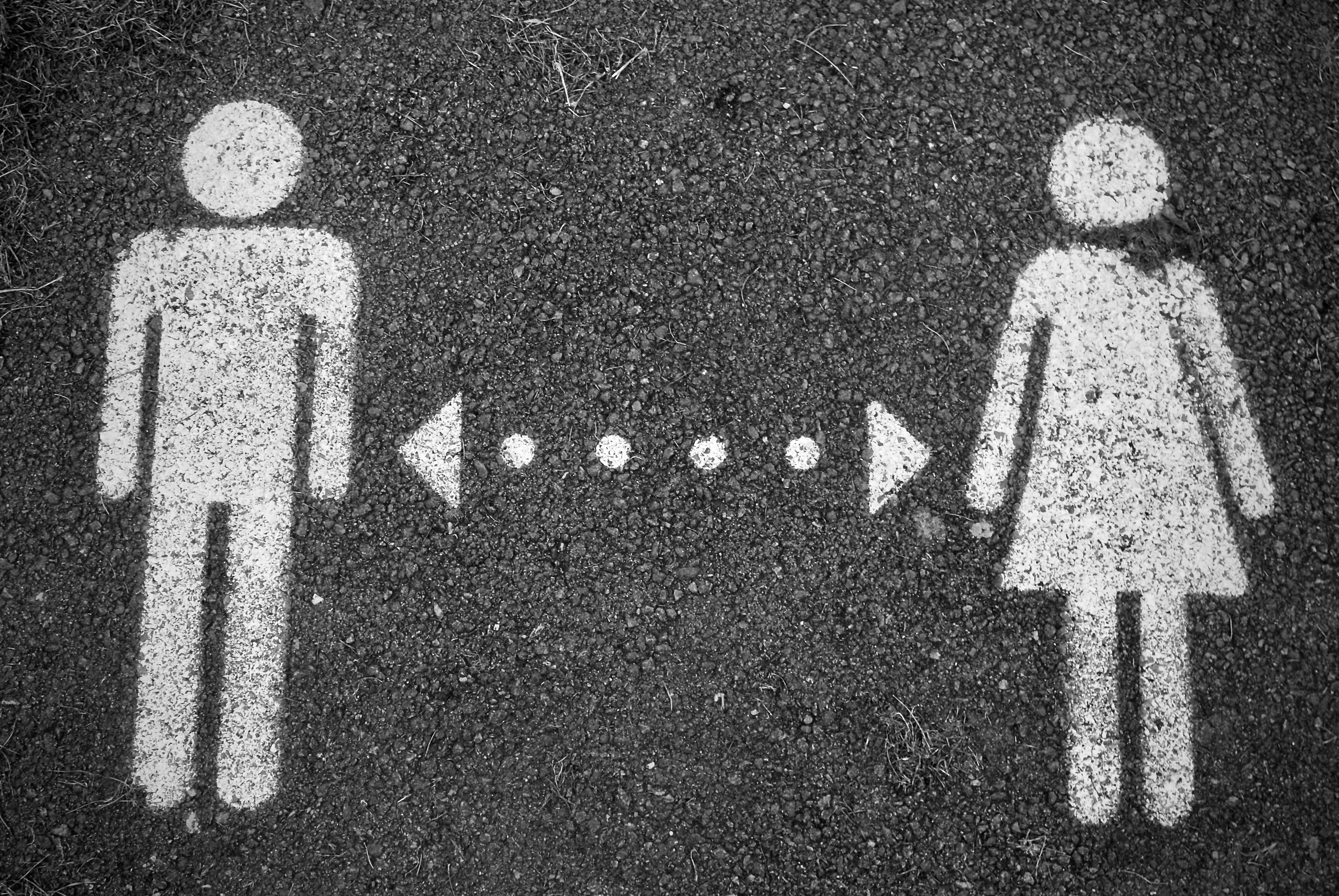 Colour photograph of a female and male symbol connected by a bi-directional arrow. Pea on unsplash.