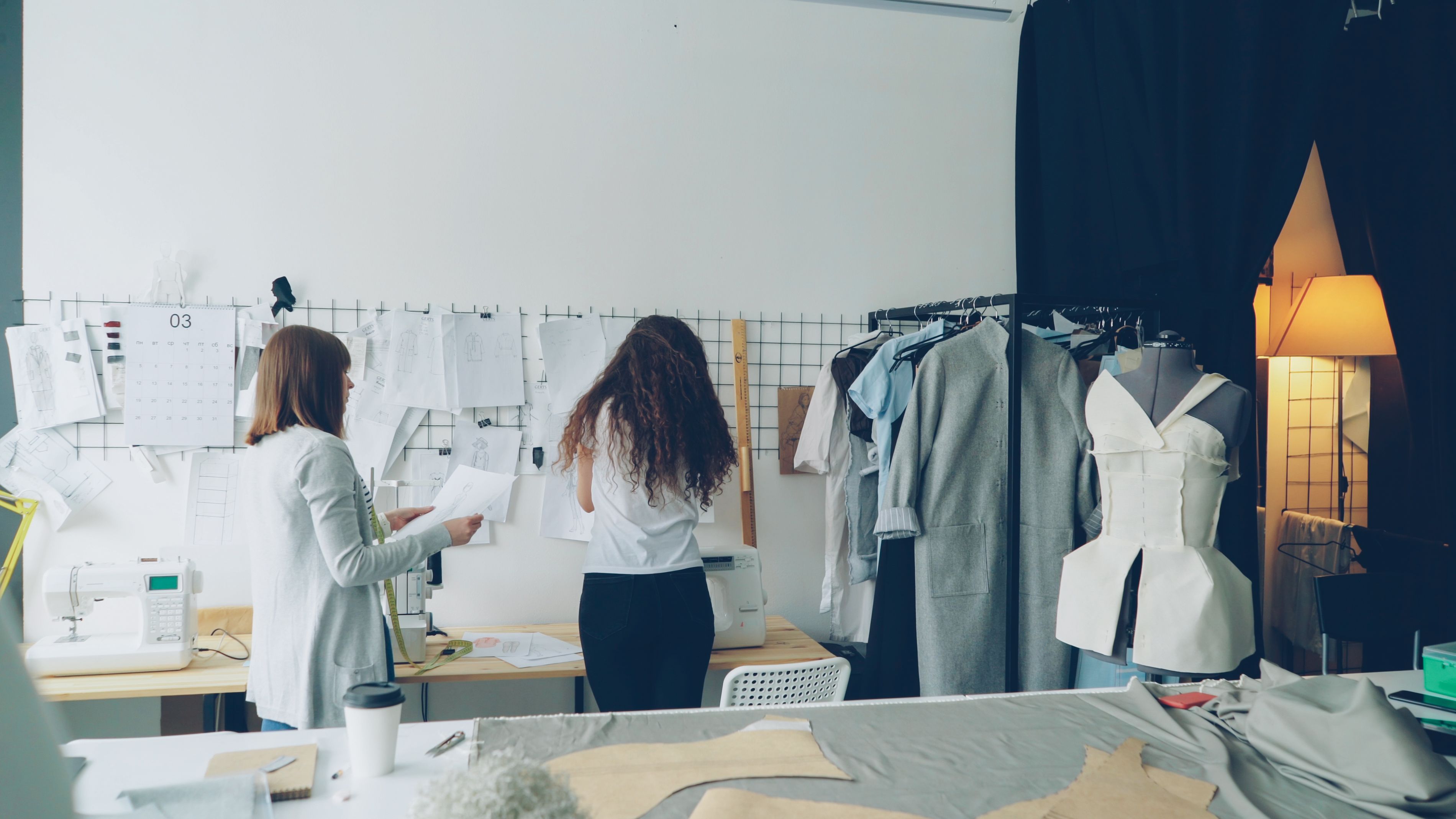 Fashion designers working on clothing sketches and patterns in a modern studio.