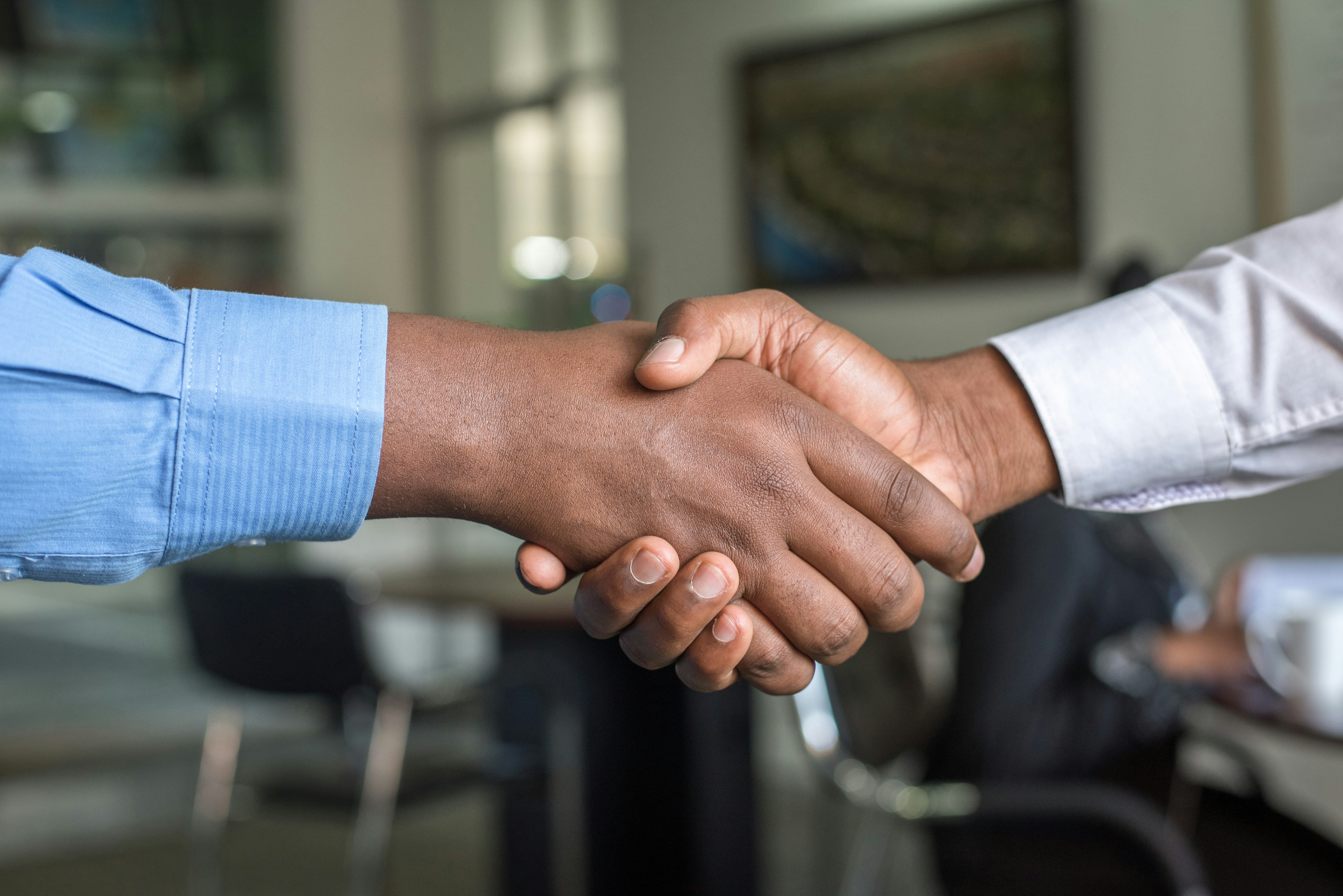 Two business professionals shaking hands during a meeting, representing networking, partnership building and international business collaboration in the textile and fashion industry.