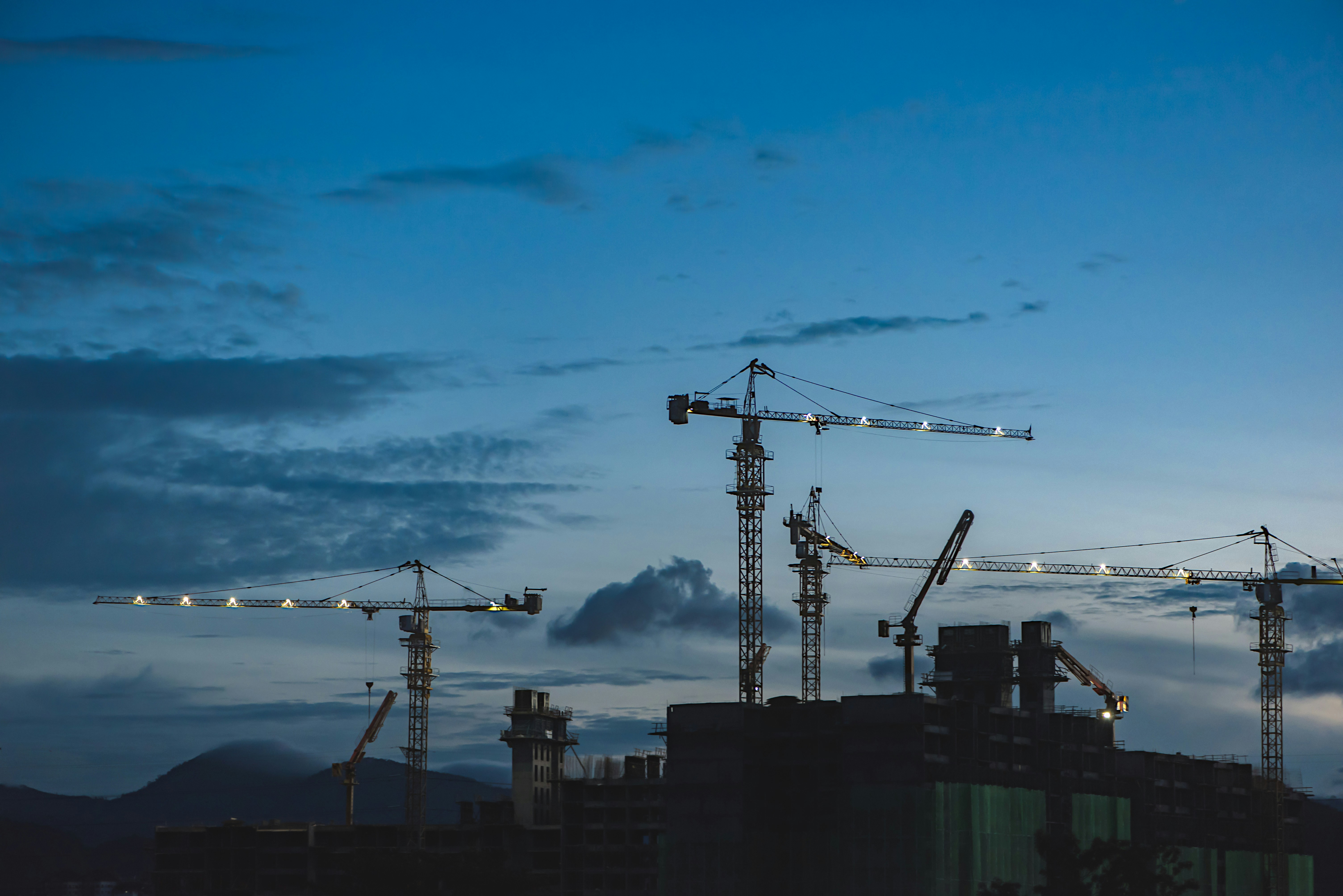 A photo presents a construction cranes.
