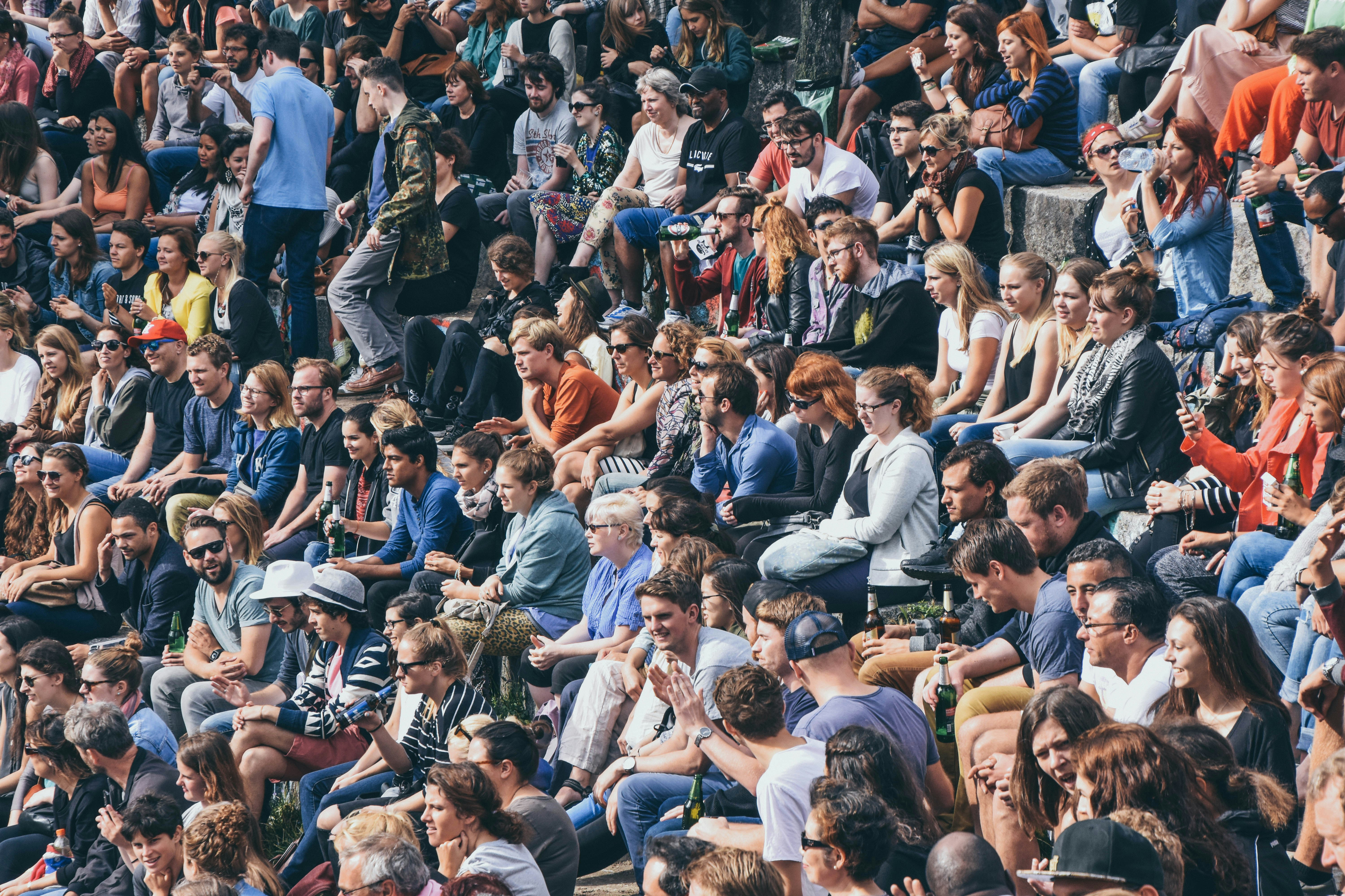 A picture presents a large crowd of people sitting together outdoors.