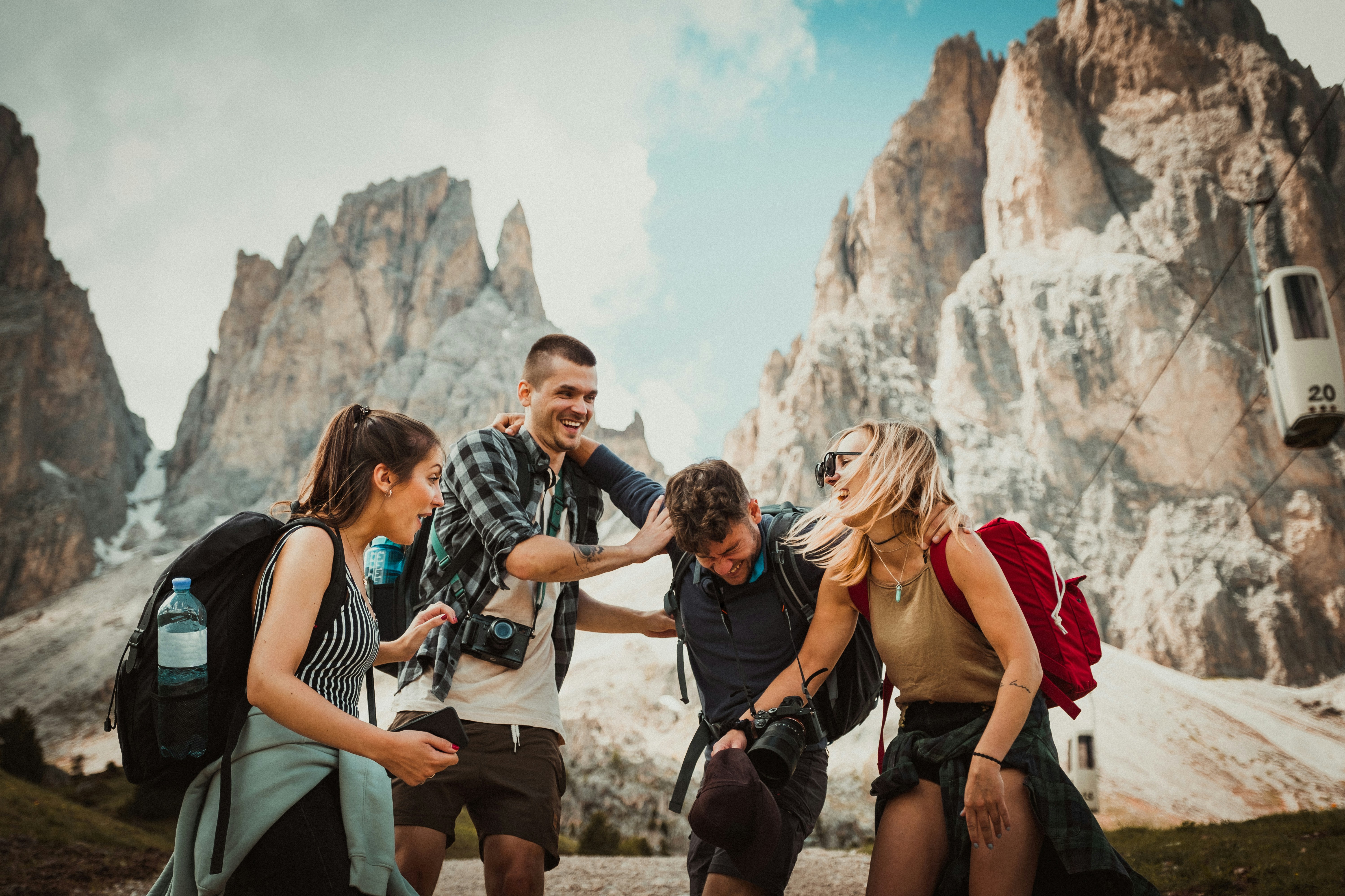 The picture presents a group of hikers laughing together in a rocky mountain setting.