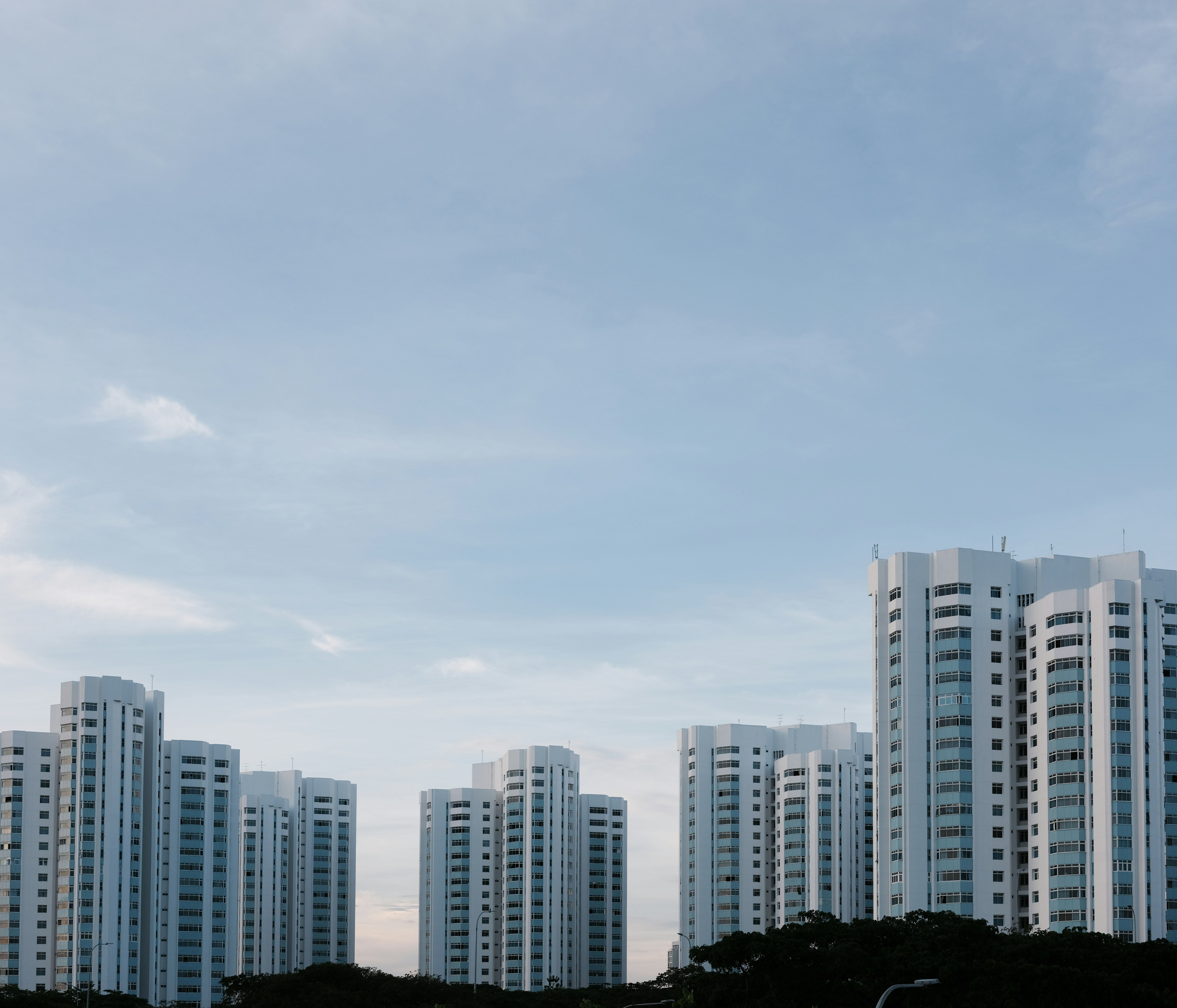A photo presents modern residential towers under a cloudy sky.