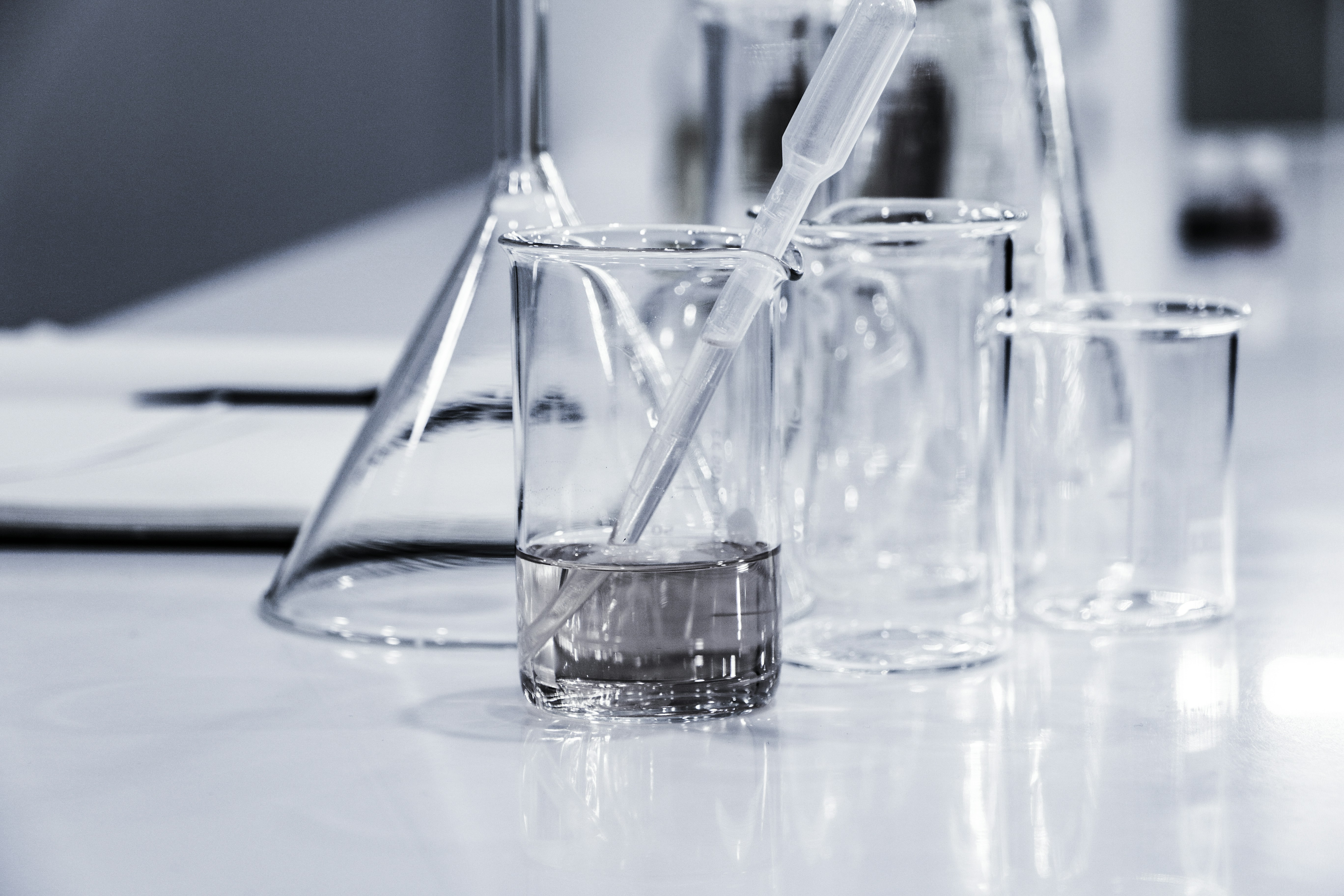 Laboratory glassware on a lab bench with a pipette in a transparent beaker containing a clear liquid.