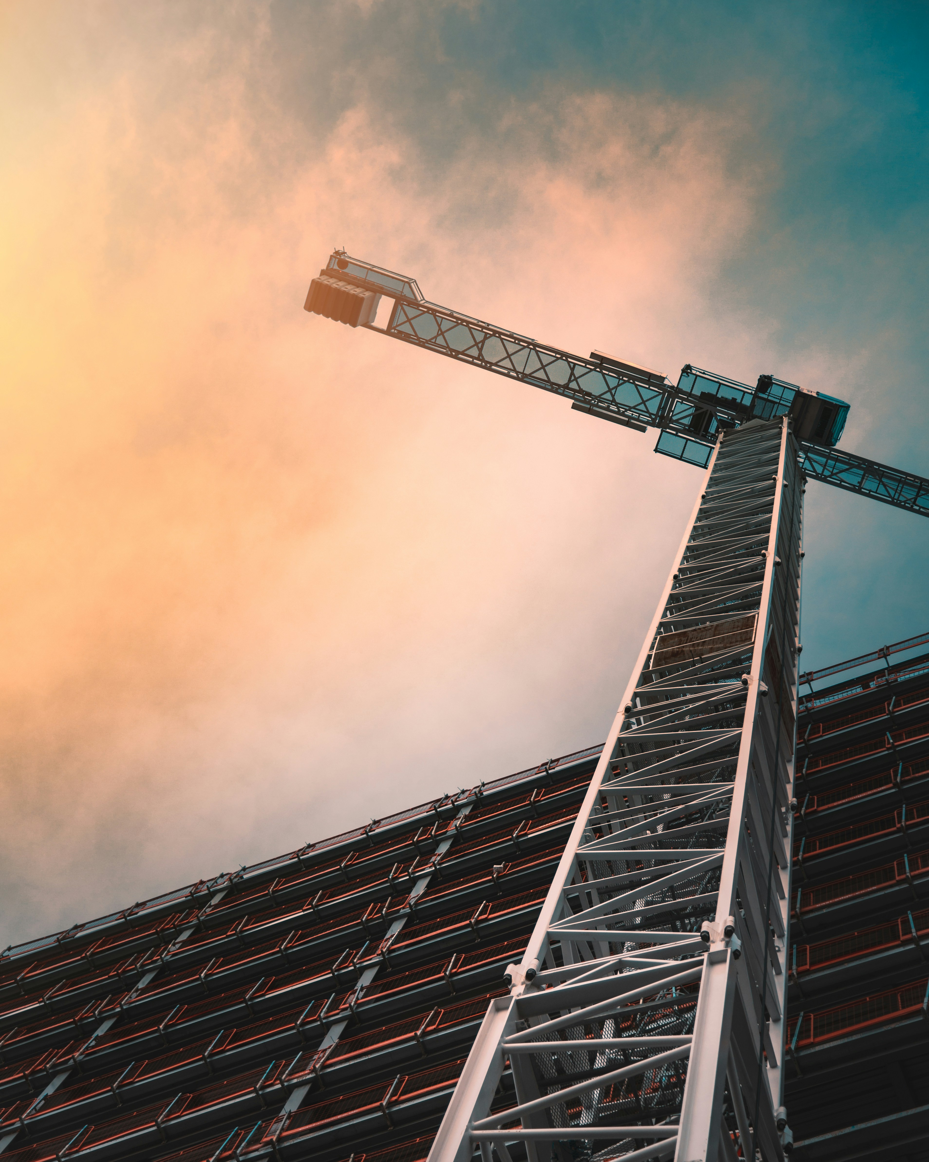 A photo presents a construction crane beside a tall building.