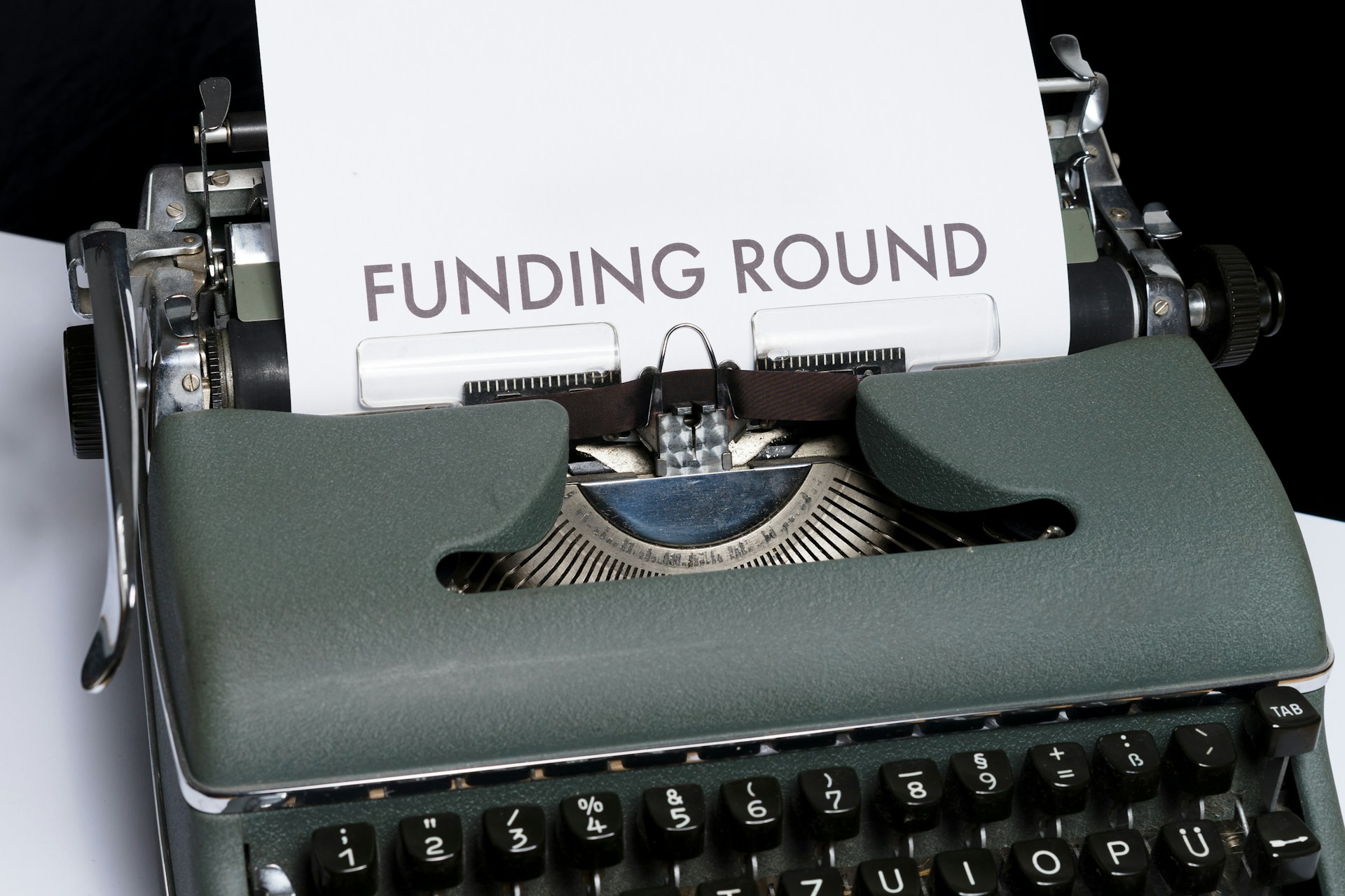 Green and white braille typewriter with paper saying ‘Funding round’. 