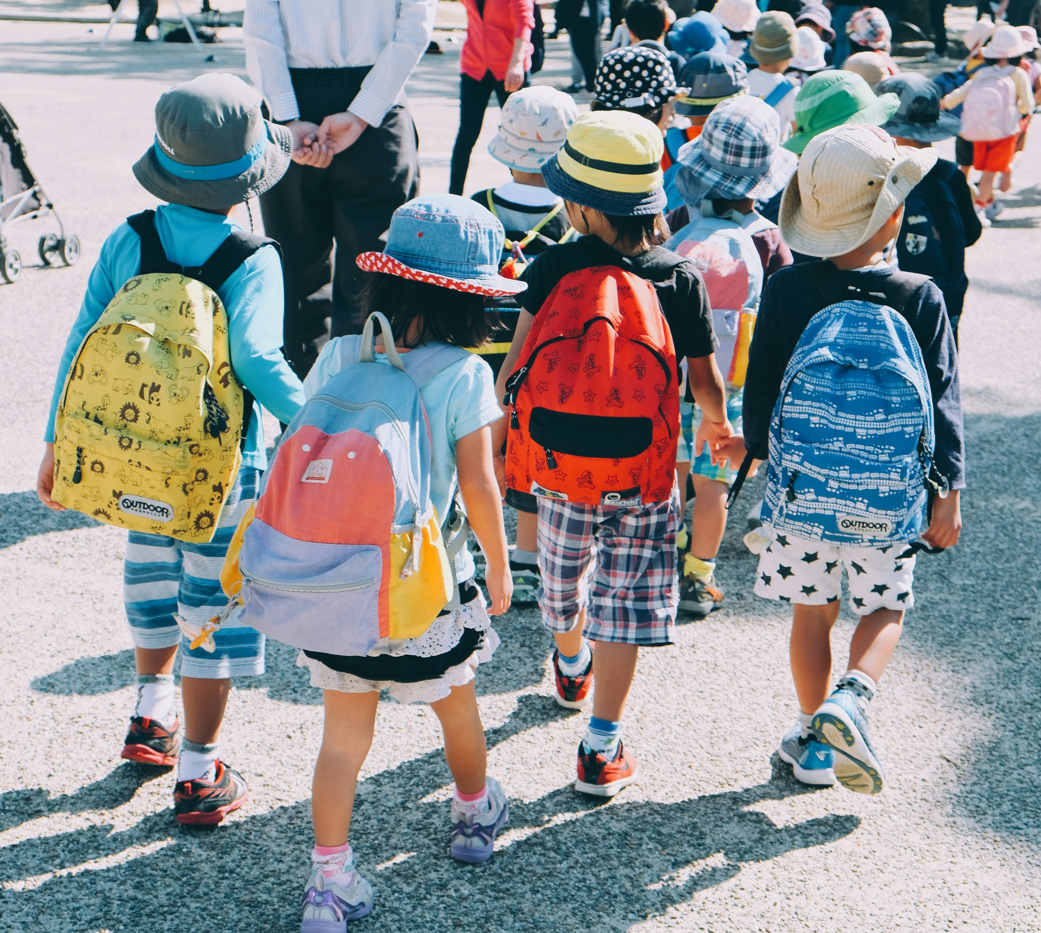 A picture presents children walking outdoors with backpacks