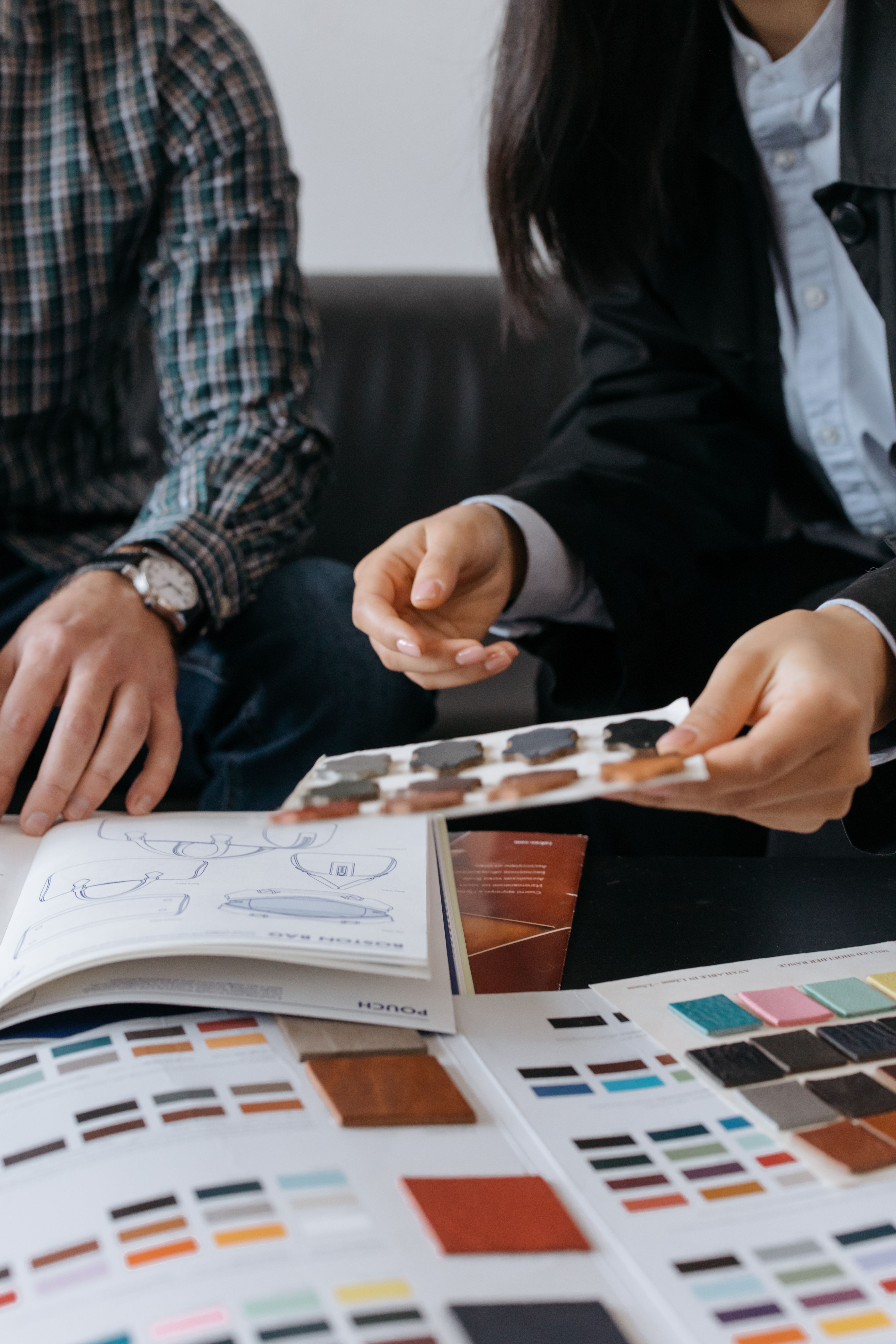 Two individuals discussing design samples and color swatches at a table, focusing on collaboration