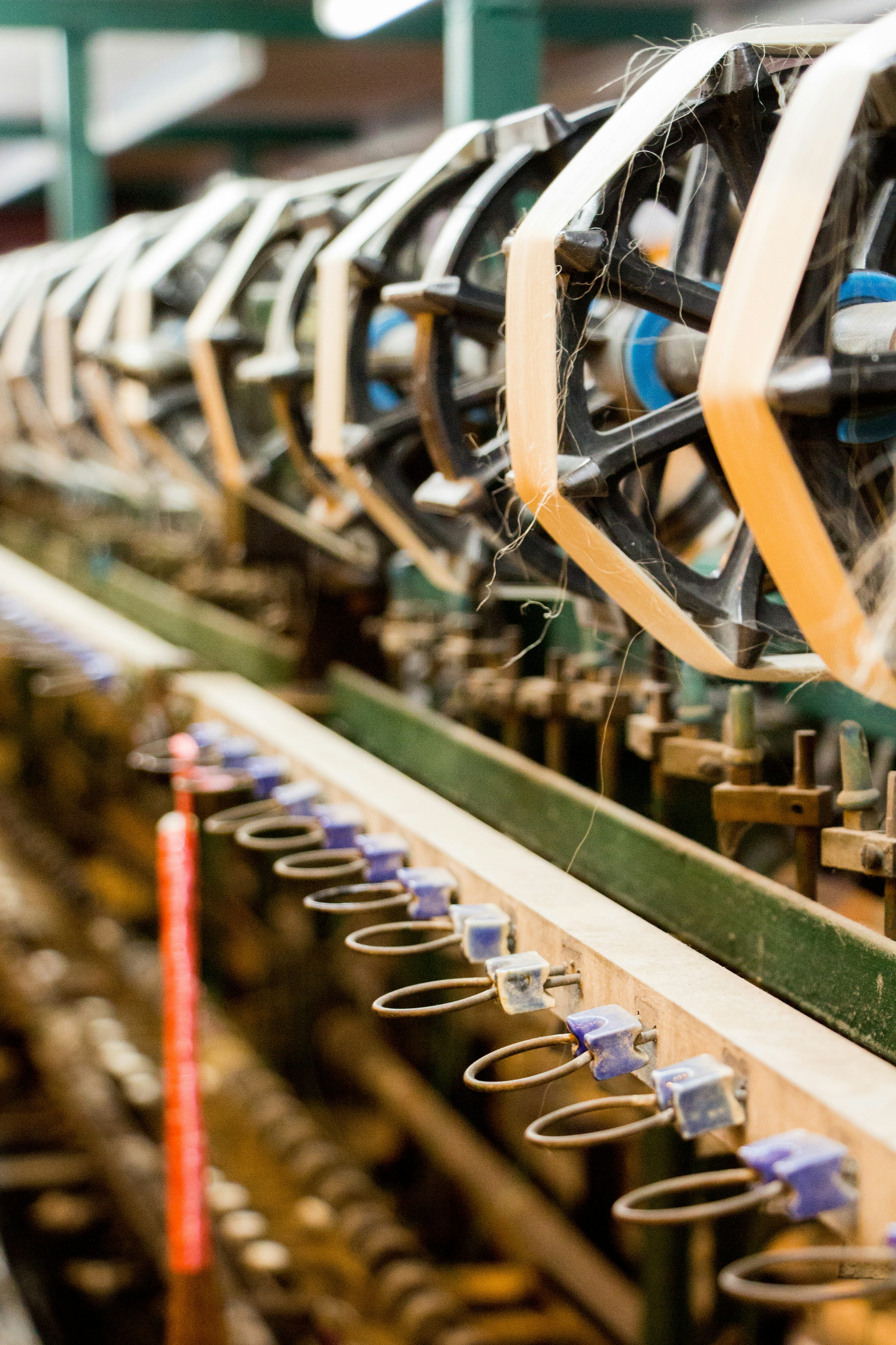Close-up of textile manufacturing machinery processing yarn in an industrial spinning facility, representing textile engineering, material performance and research into durable textile products.
