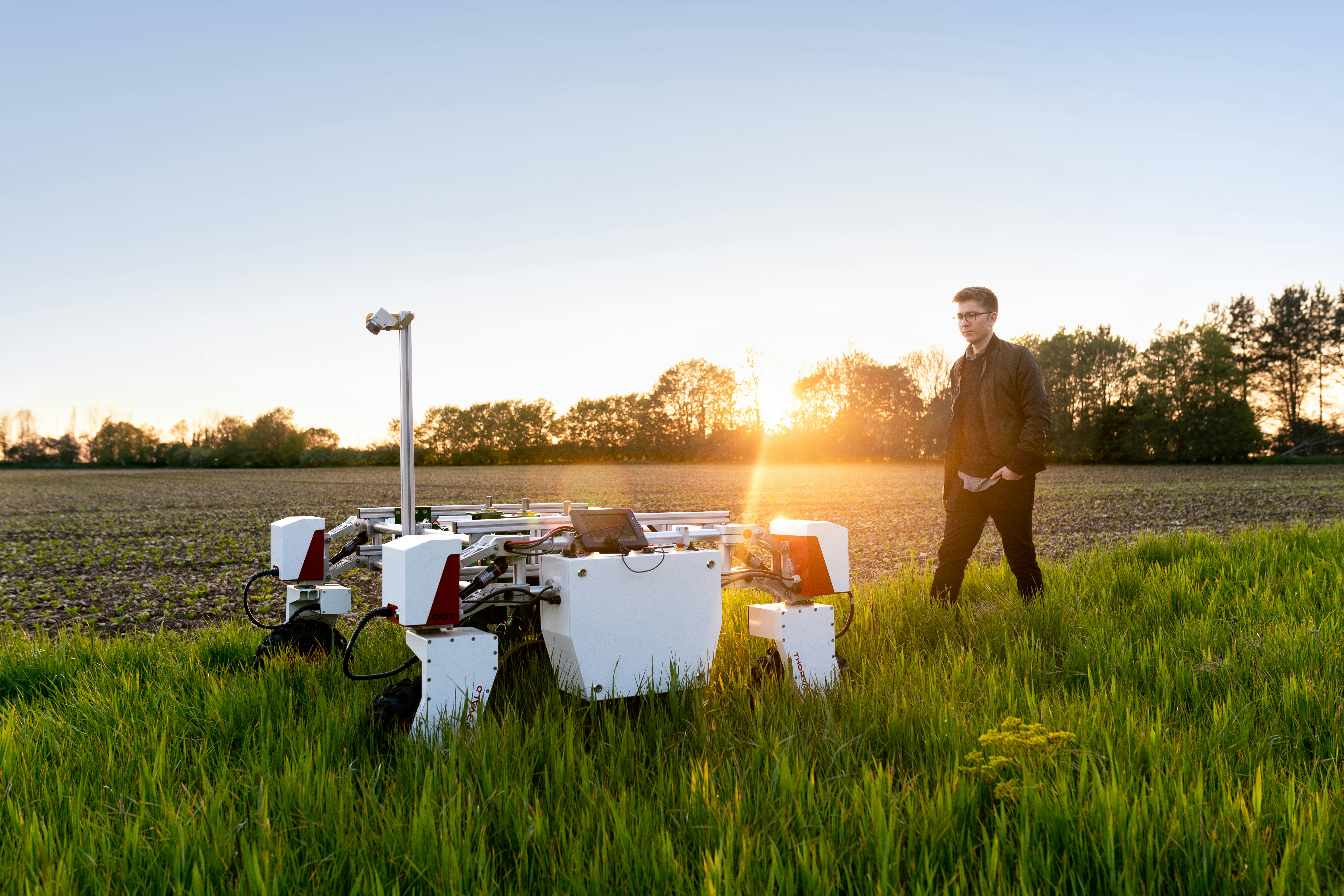 A photo presents a person inspecting agricultural technology in a field.