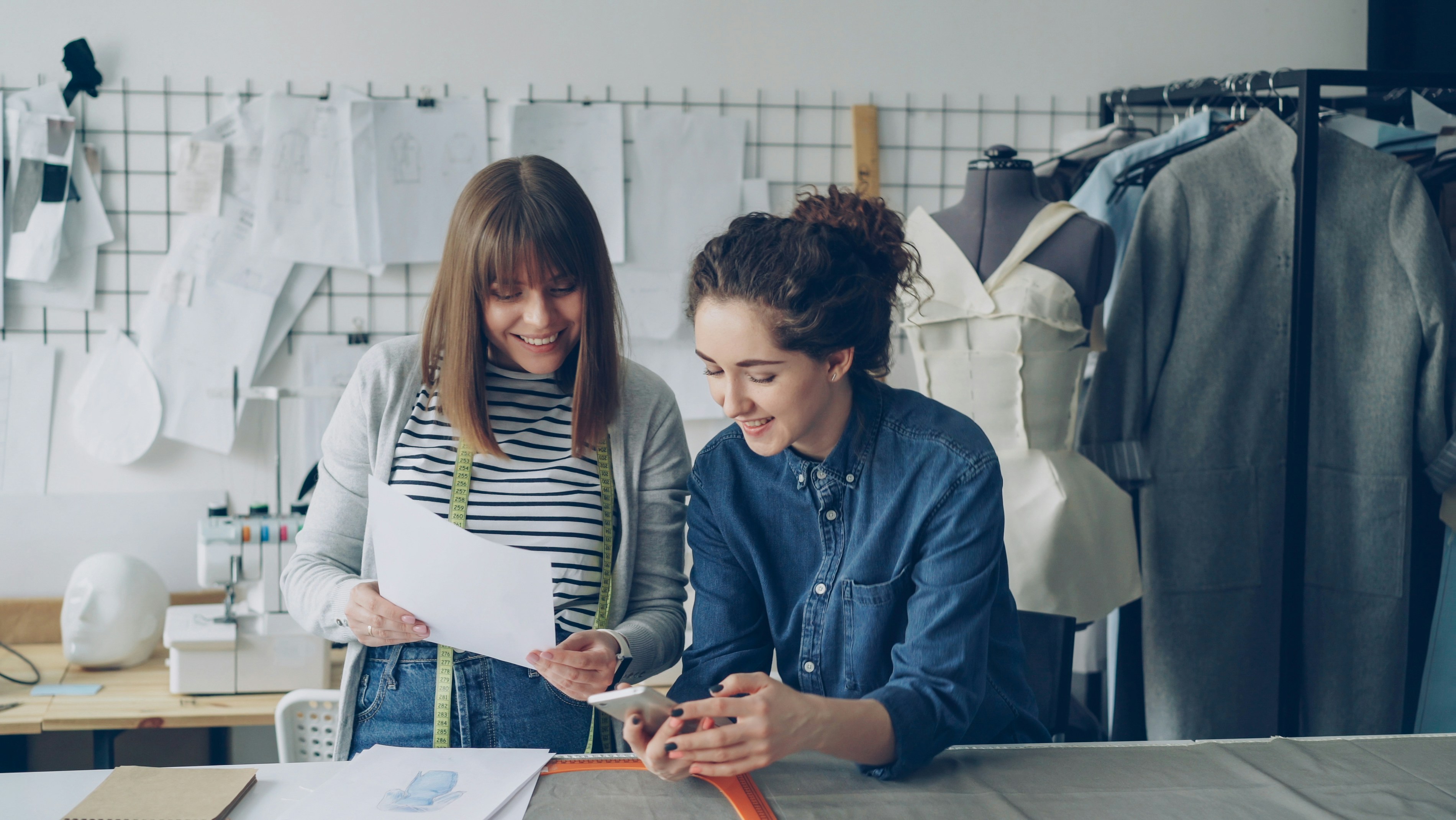 Two designers collaborate, reviewing plans with smiles.