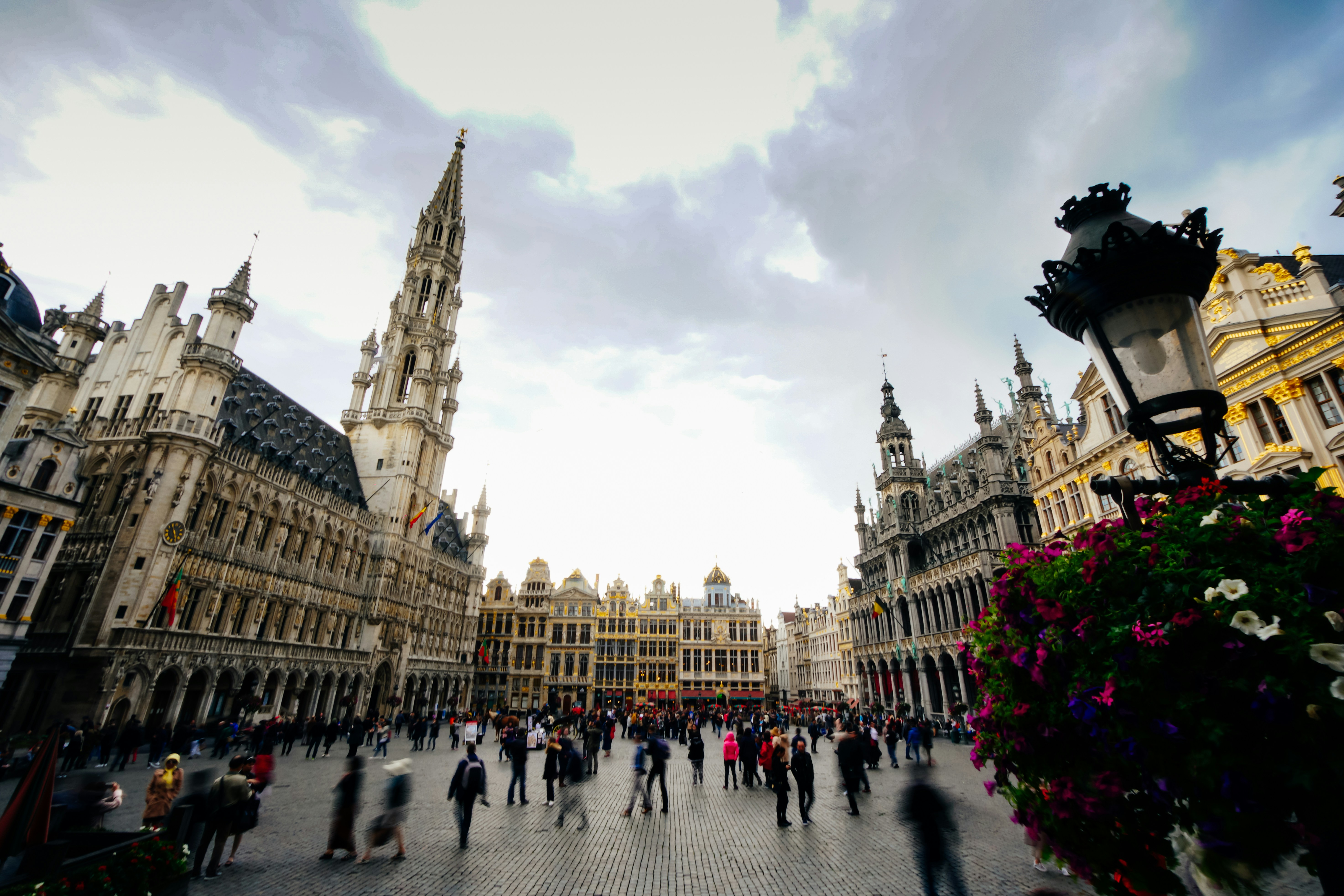 A picture presents a historic city square with grand buildings and people.