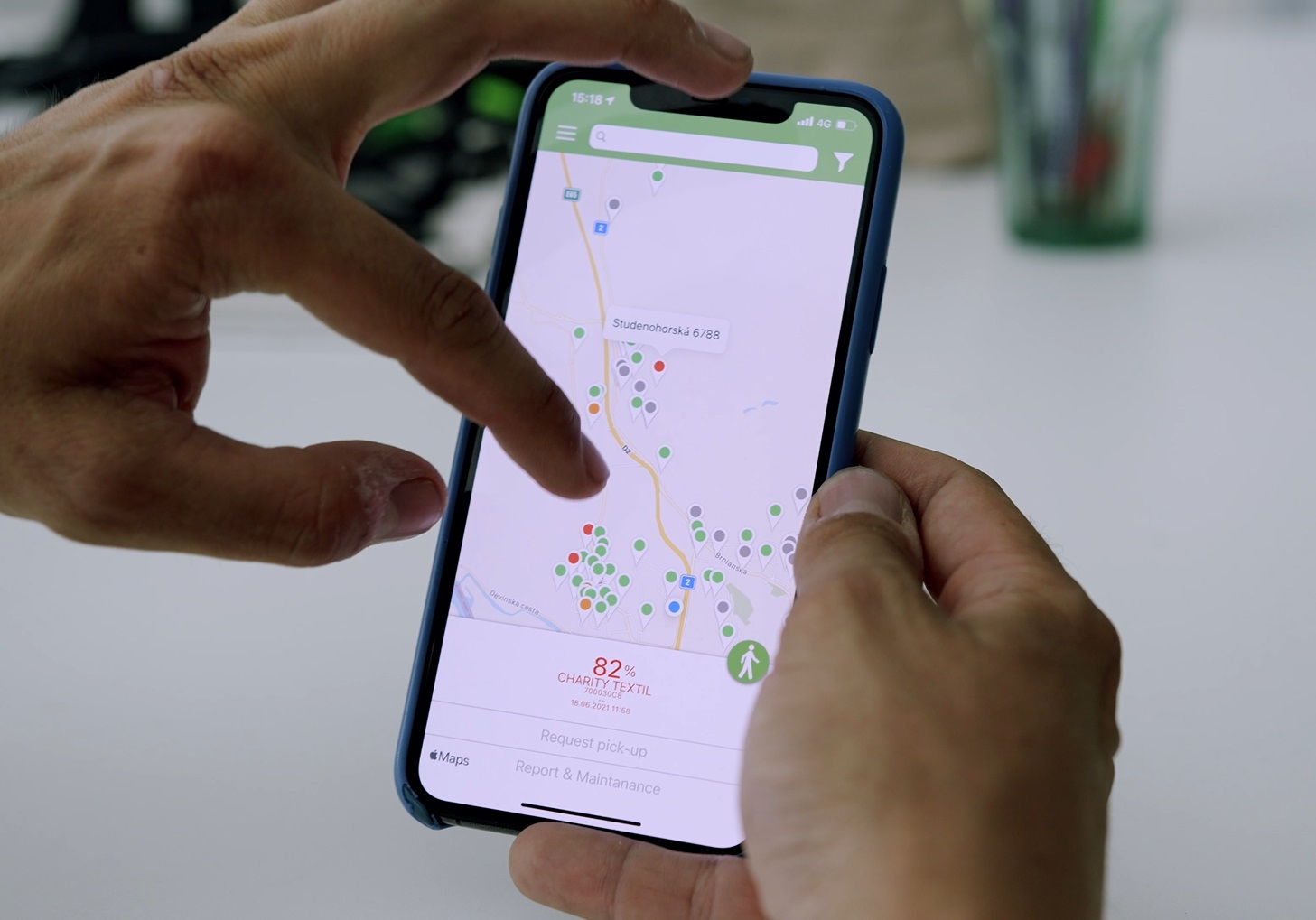 Hands holding a smartphone displaying a map of textile collection points.