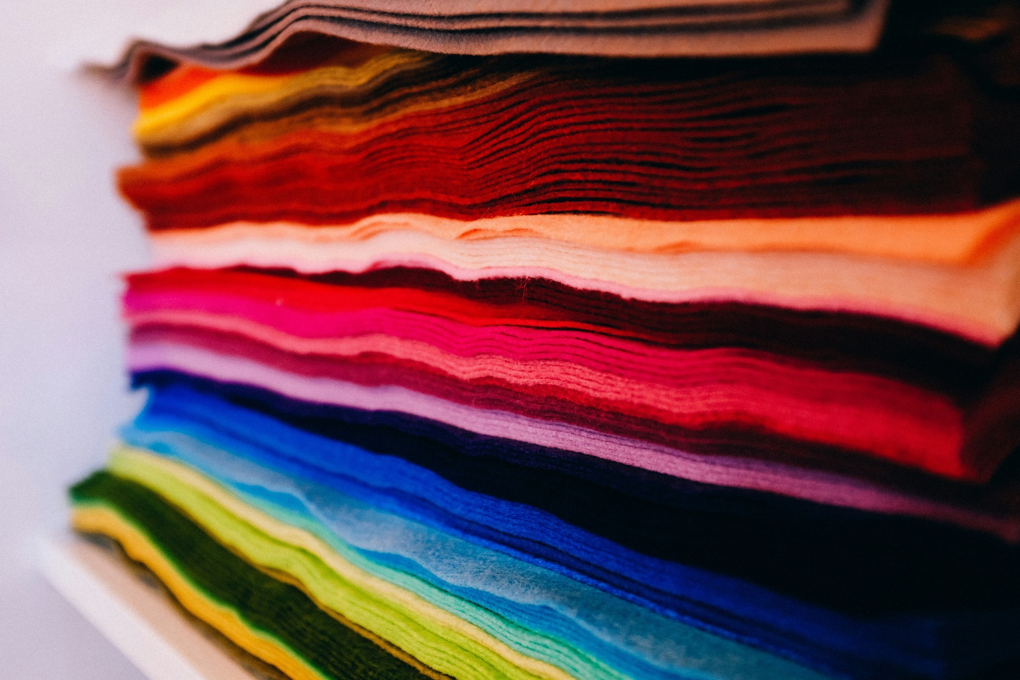 Stack of colourful textile fabrics in red, pink, orange, blue, green and neutral tones