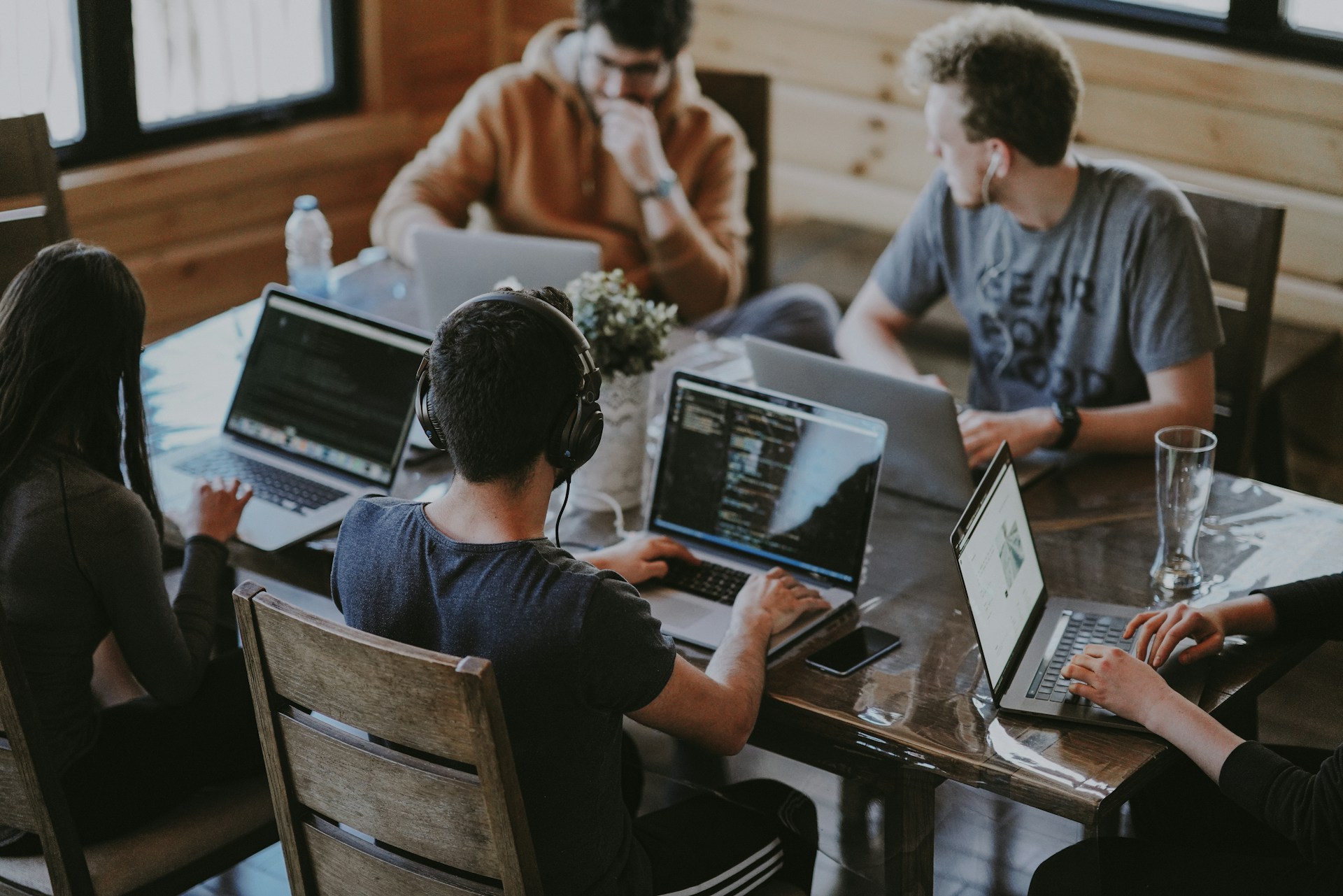 The photo presents a group of people working on laptops together.