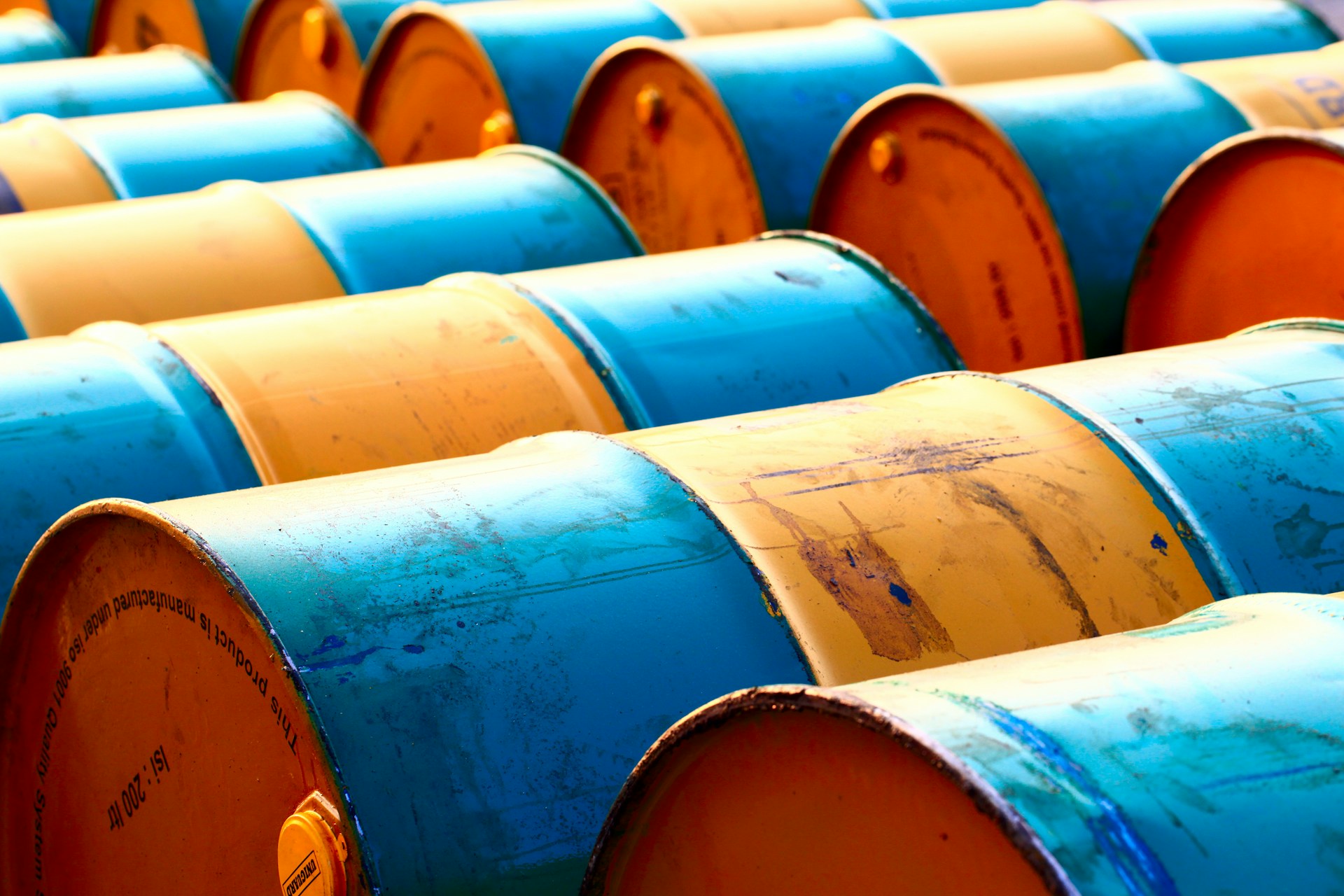 The photo presents rows of industrial barrels.