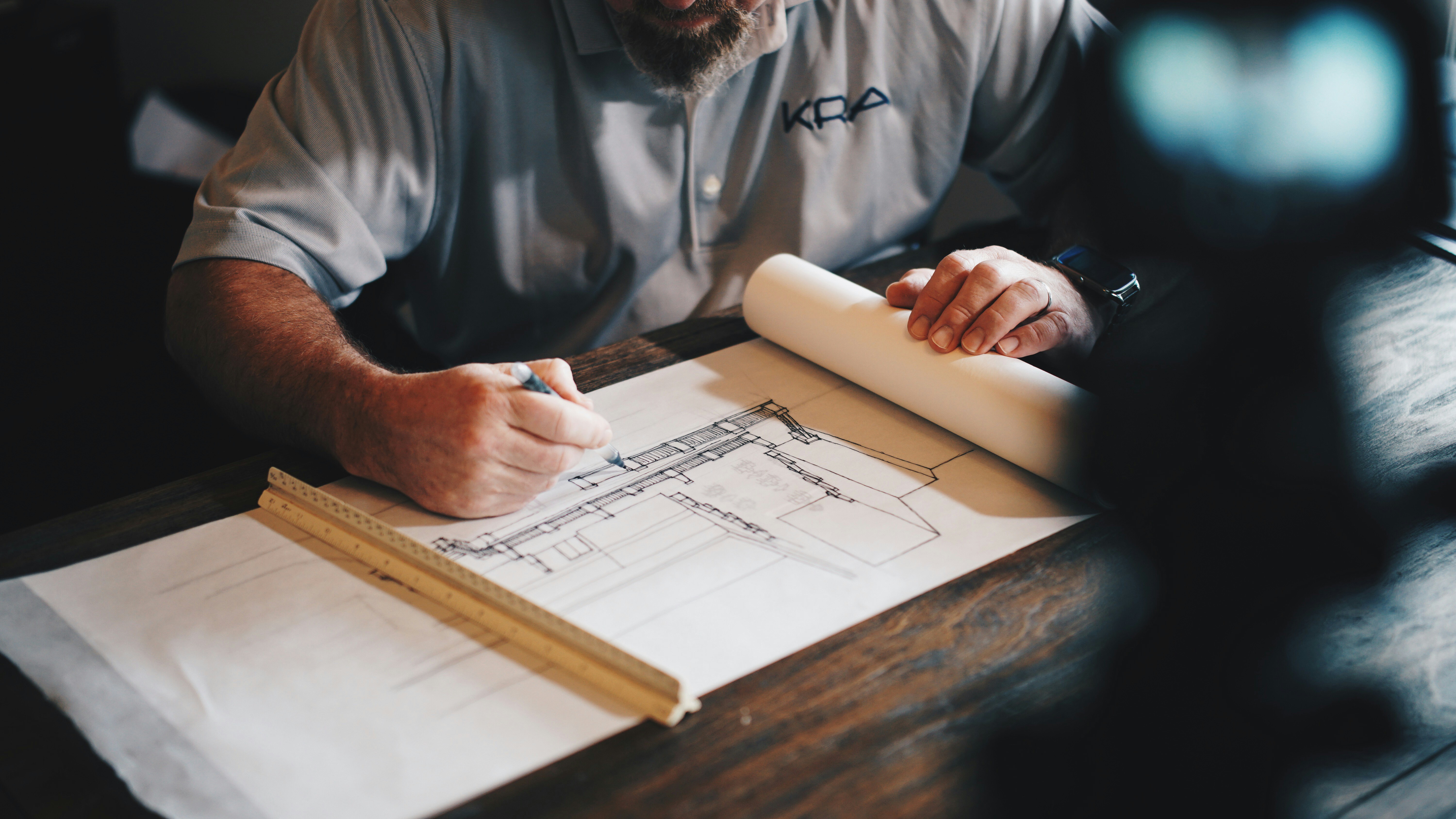 The picture describes an architect reviewing building plans.