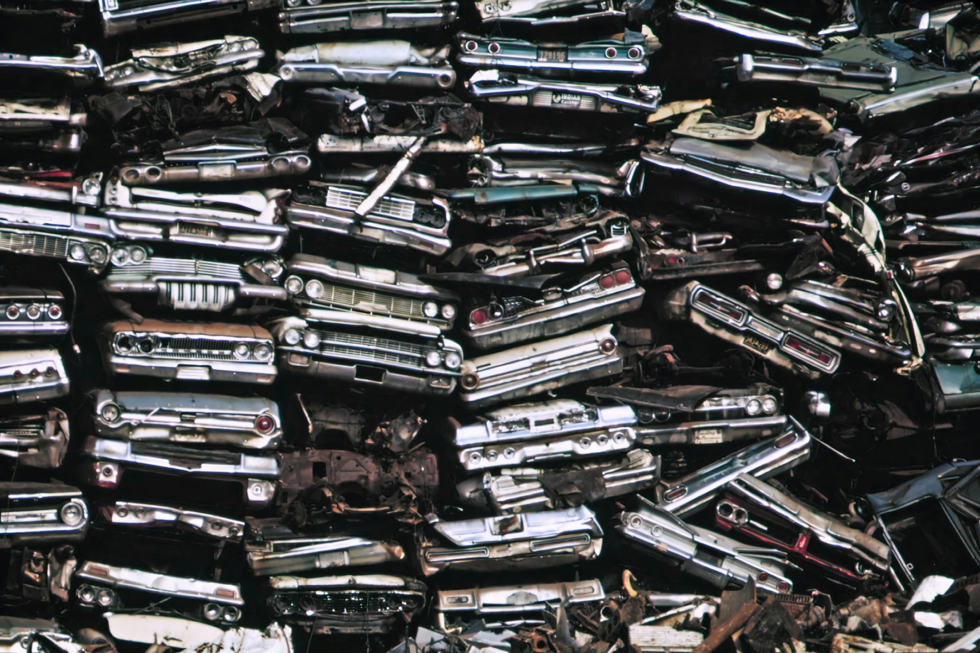 The photo presents a pile of old cars.