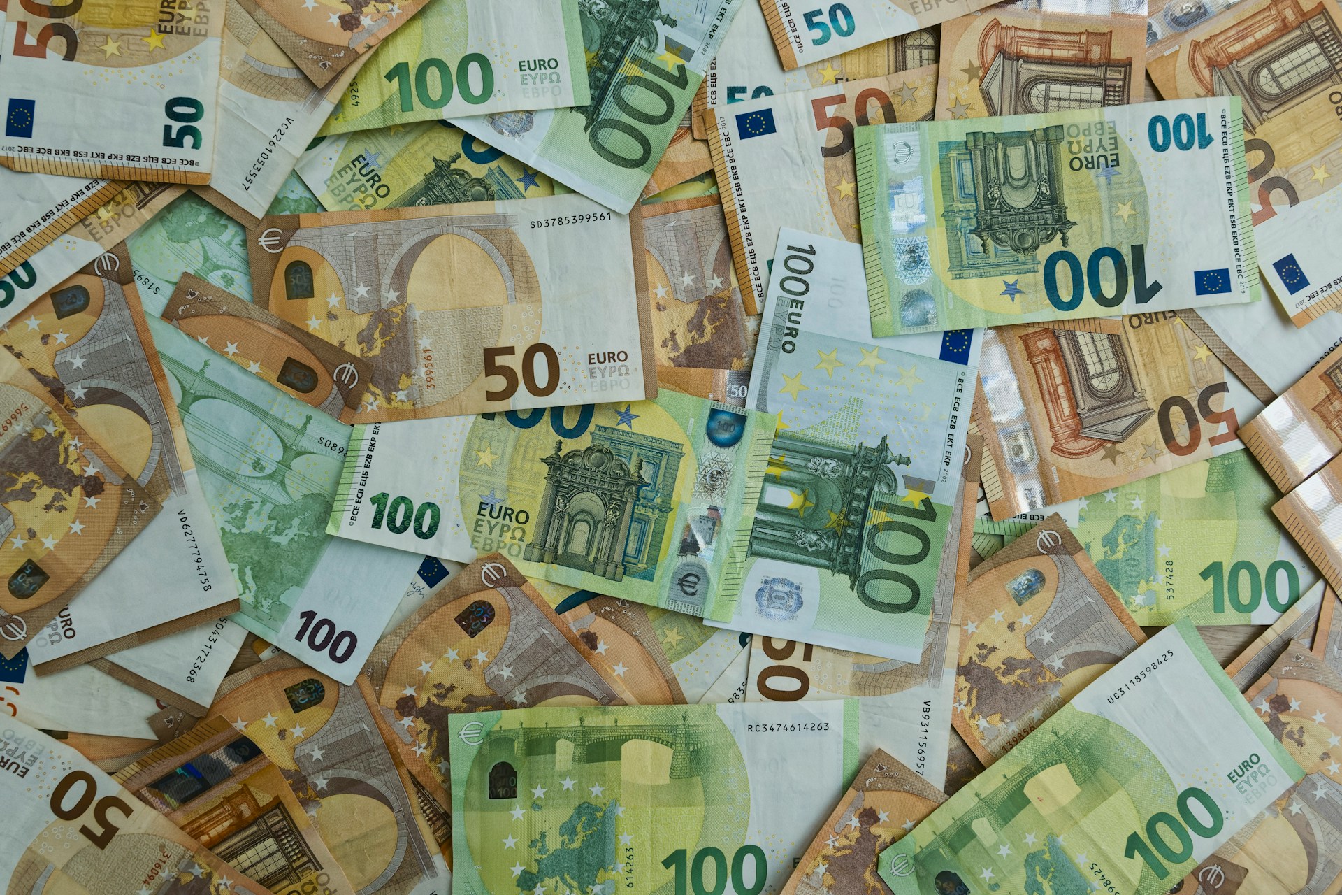 The photo presents a collection of €50 and €100 euro banknotes.