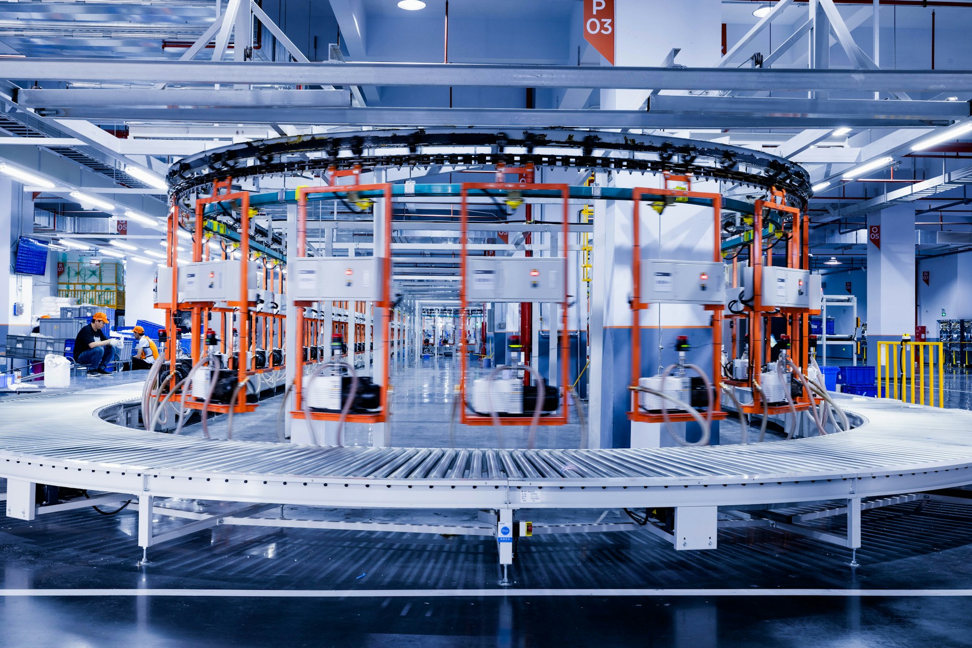The photo presents a large automated industrial production line with conveyor systems and machinery inside a modern factory.