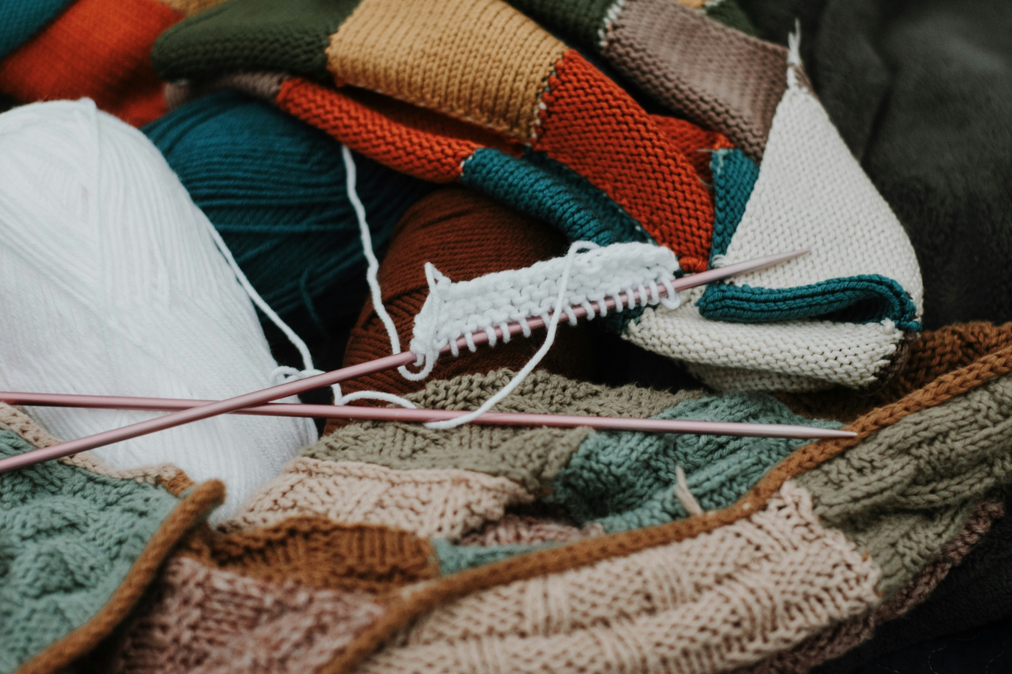 Colourful yarn, knitted textiles and knitting needles representing textile crafts and creative production.