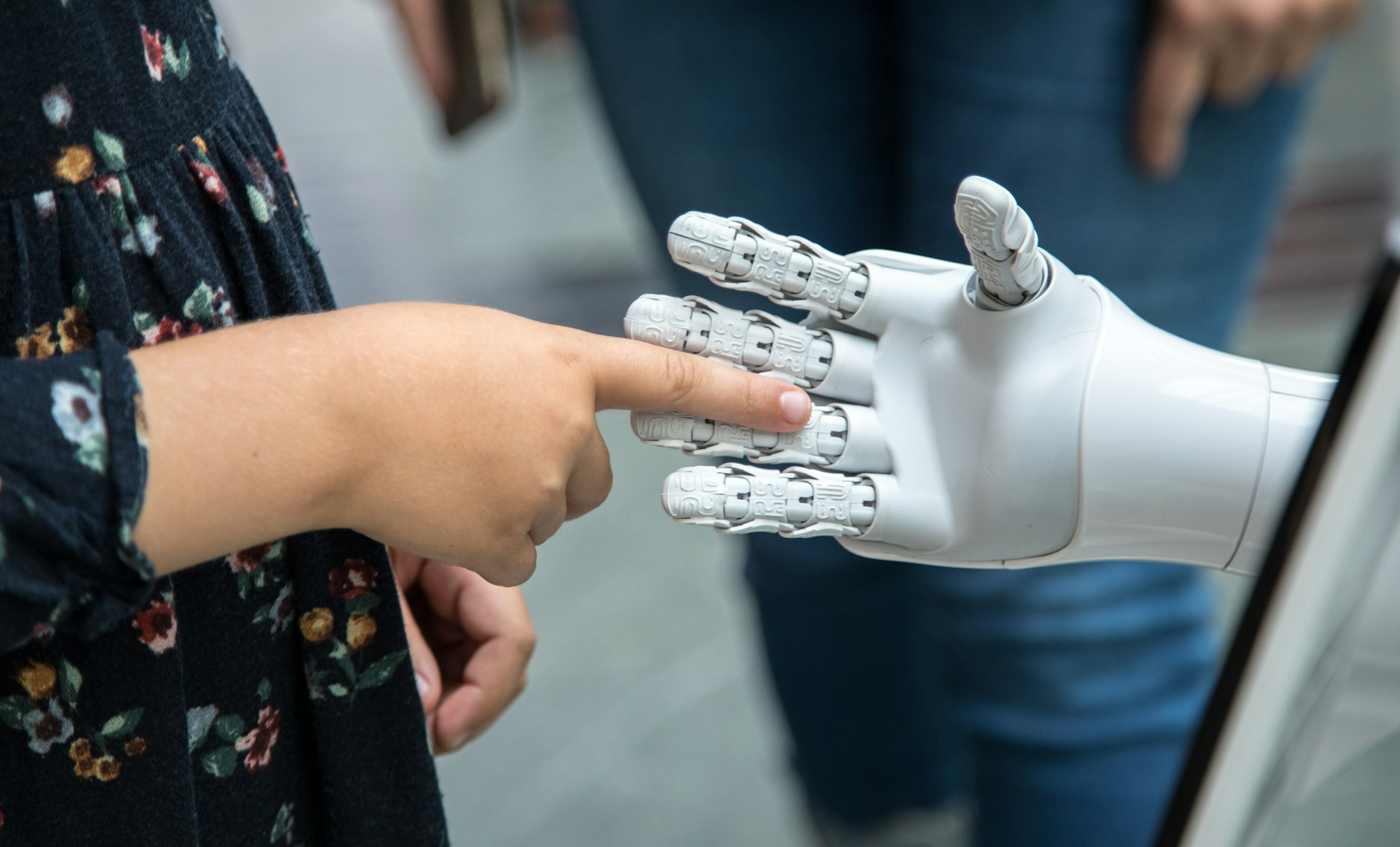The photo presents a person interacting with a robotic hand.