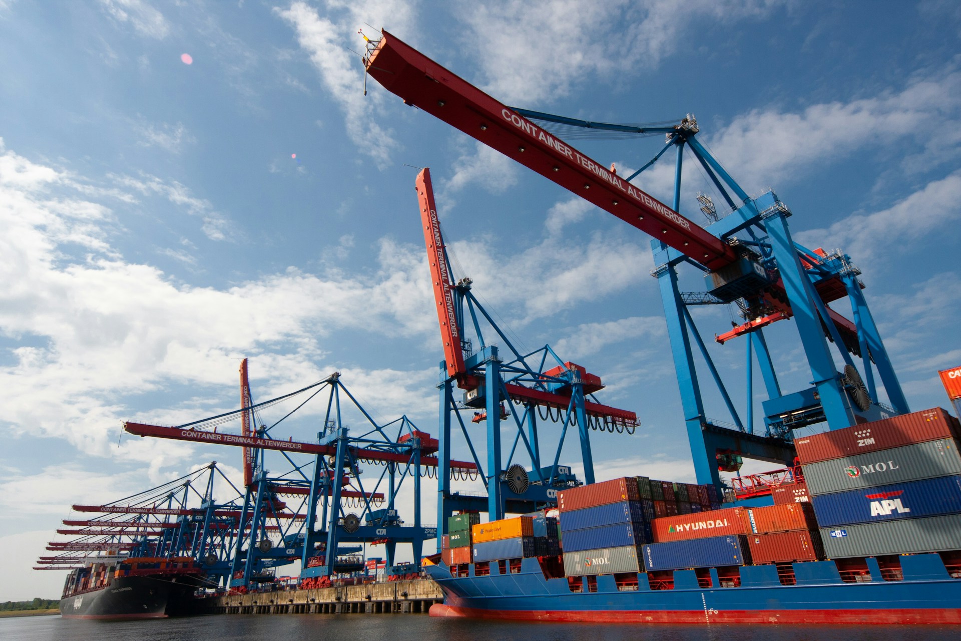 The photo presents container ships and cranes at a port.