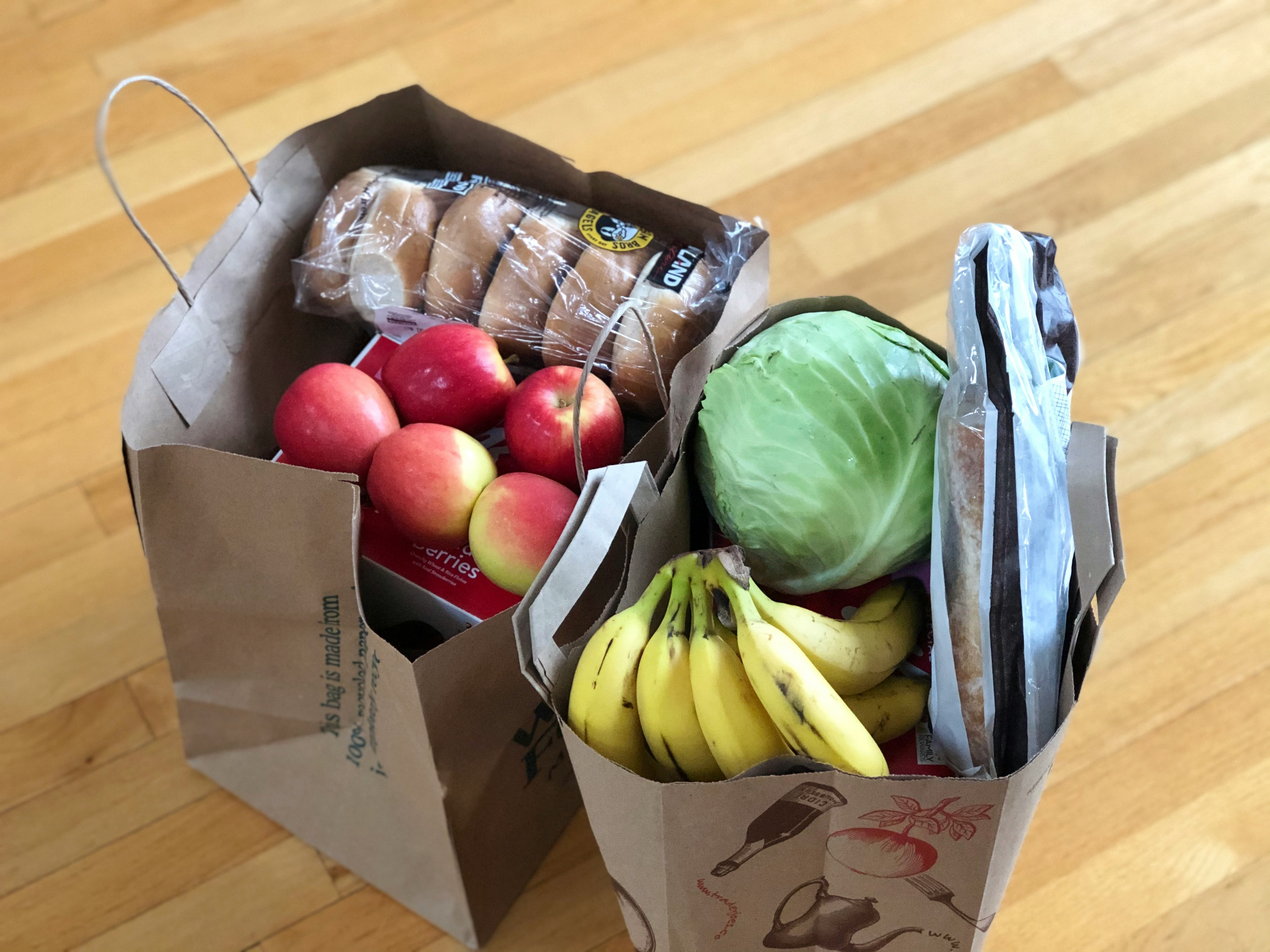 The photo presents two grocery bags filled with food.