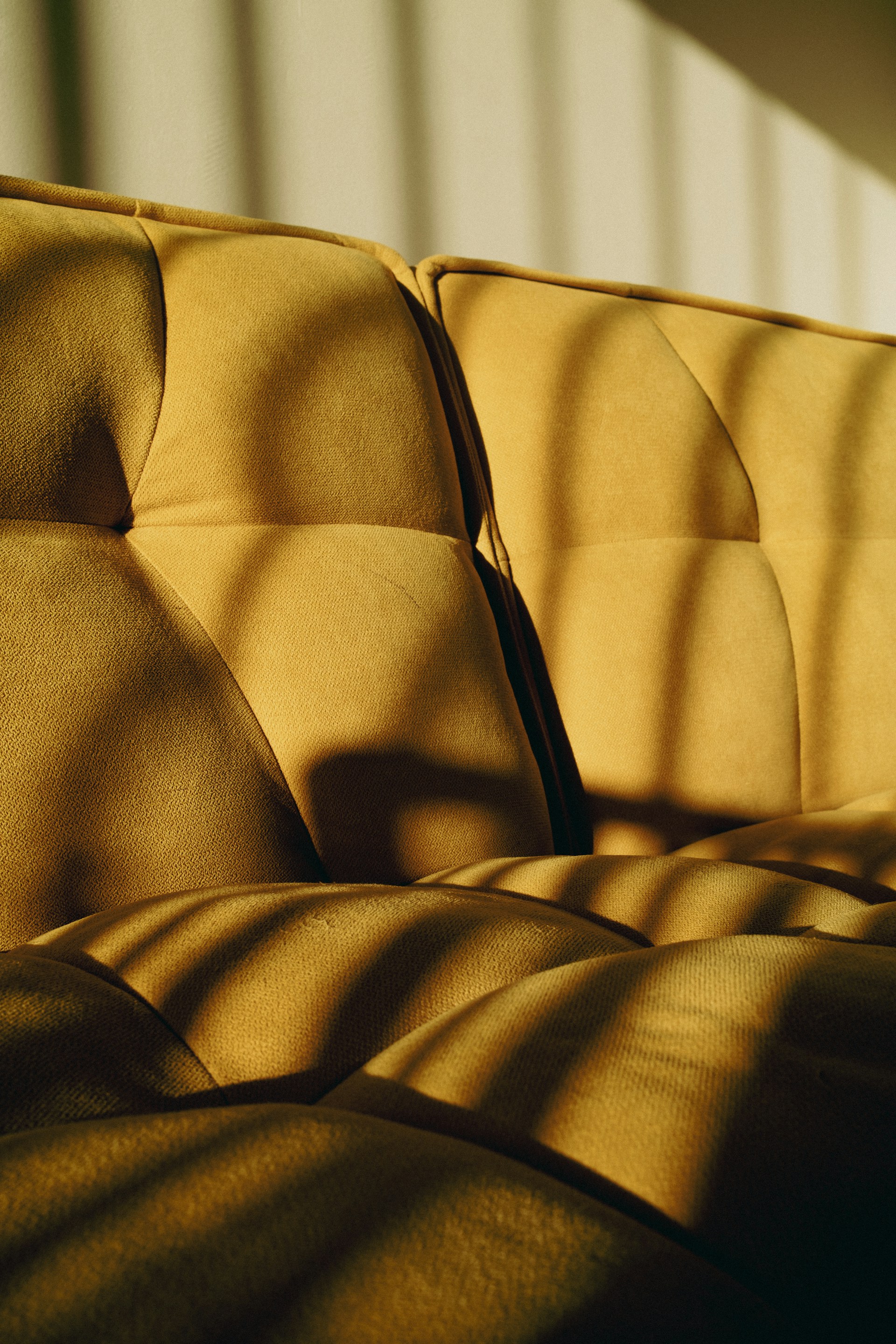 A yellow upholstered sofa with a textured fabric.