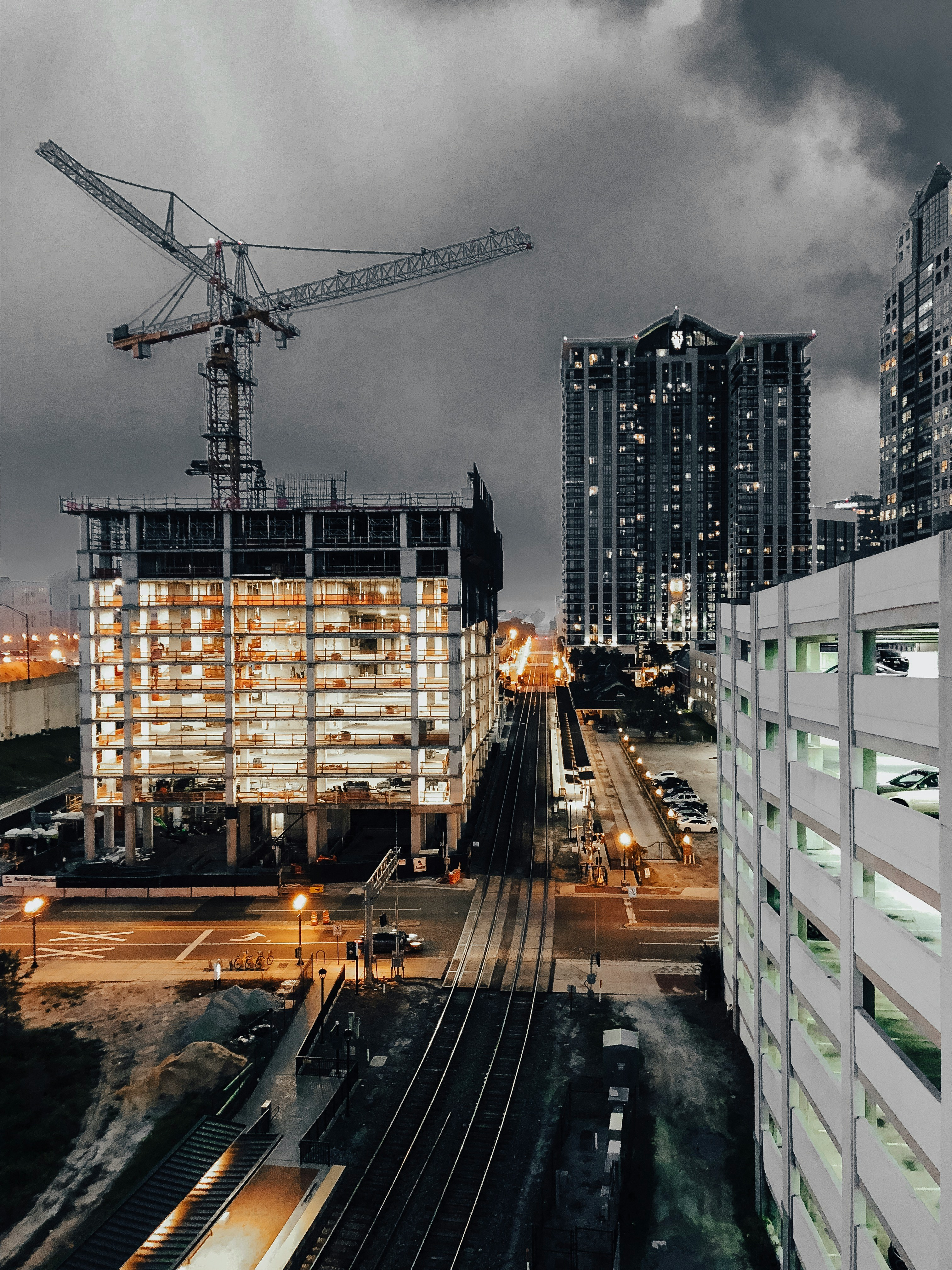 The picture presents a high-rise building under construction with cranes overhead.