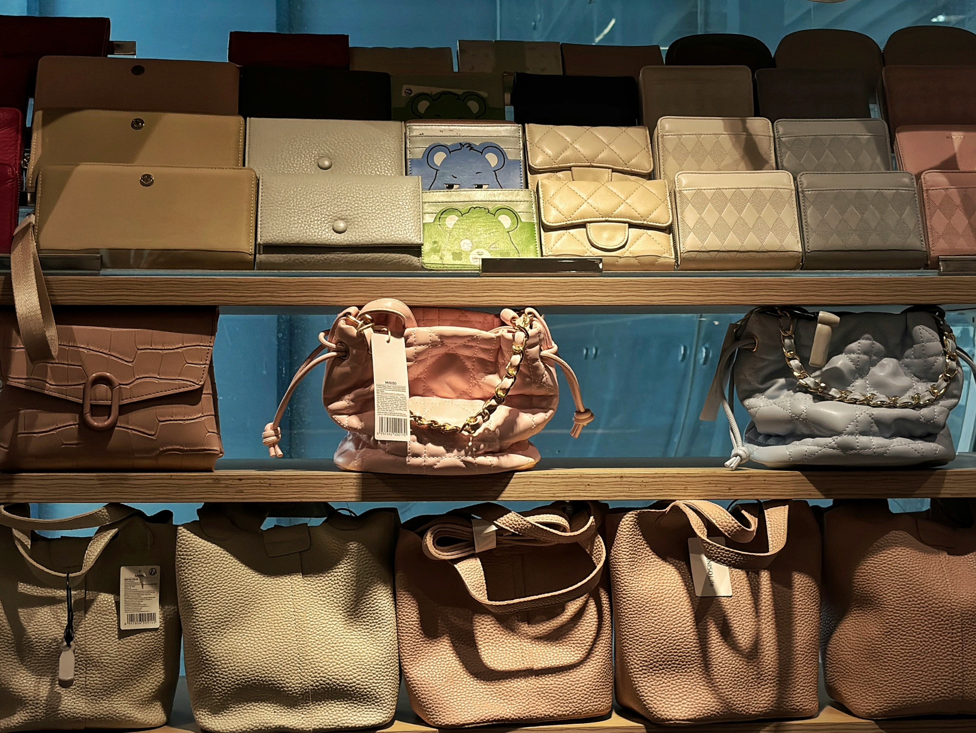 Handbags, wallets and fashion accessories displayed on shelves in a retail setting.