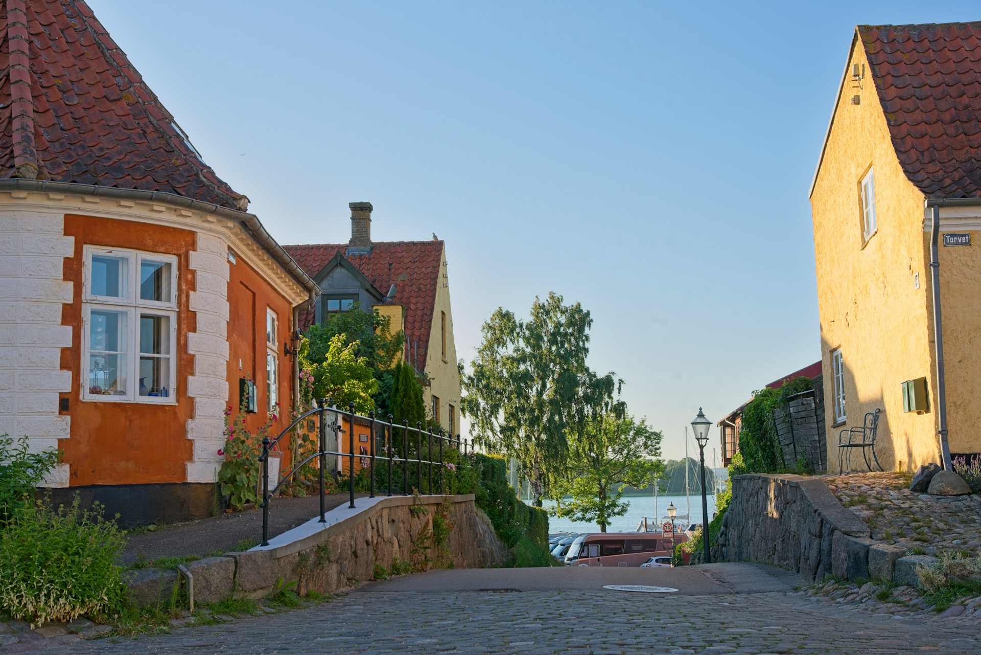 The photo presents a quiet street in Denmark with colourful historic houses leading toward the waterfront.