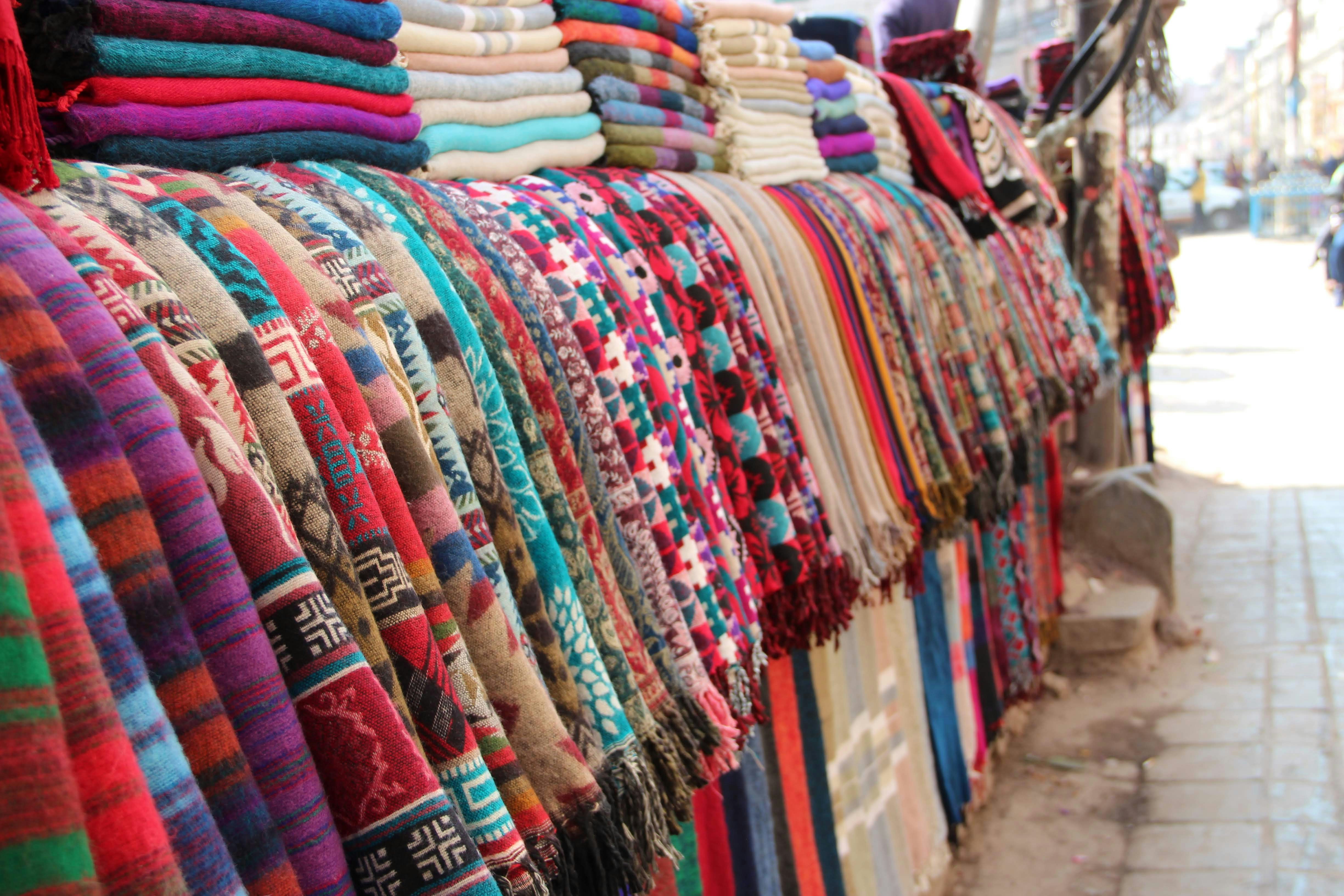 Colourful textiles and patterned fabrics displayed at a fashion market.