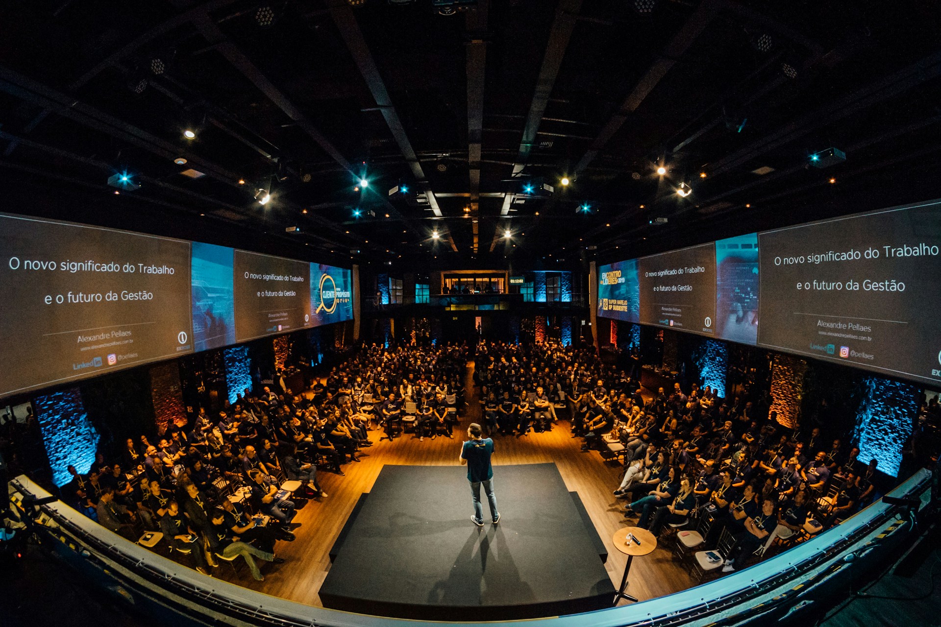 The photo presents a speaker addressing a conference audience.