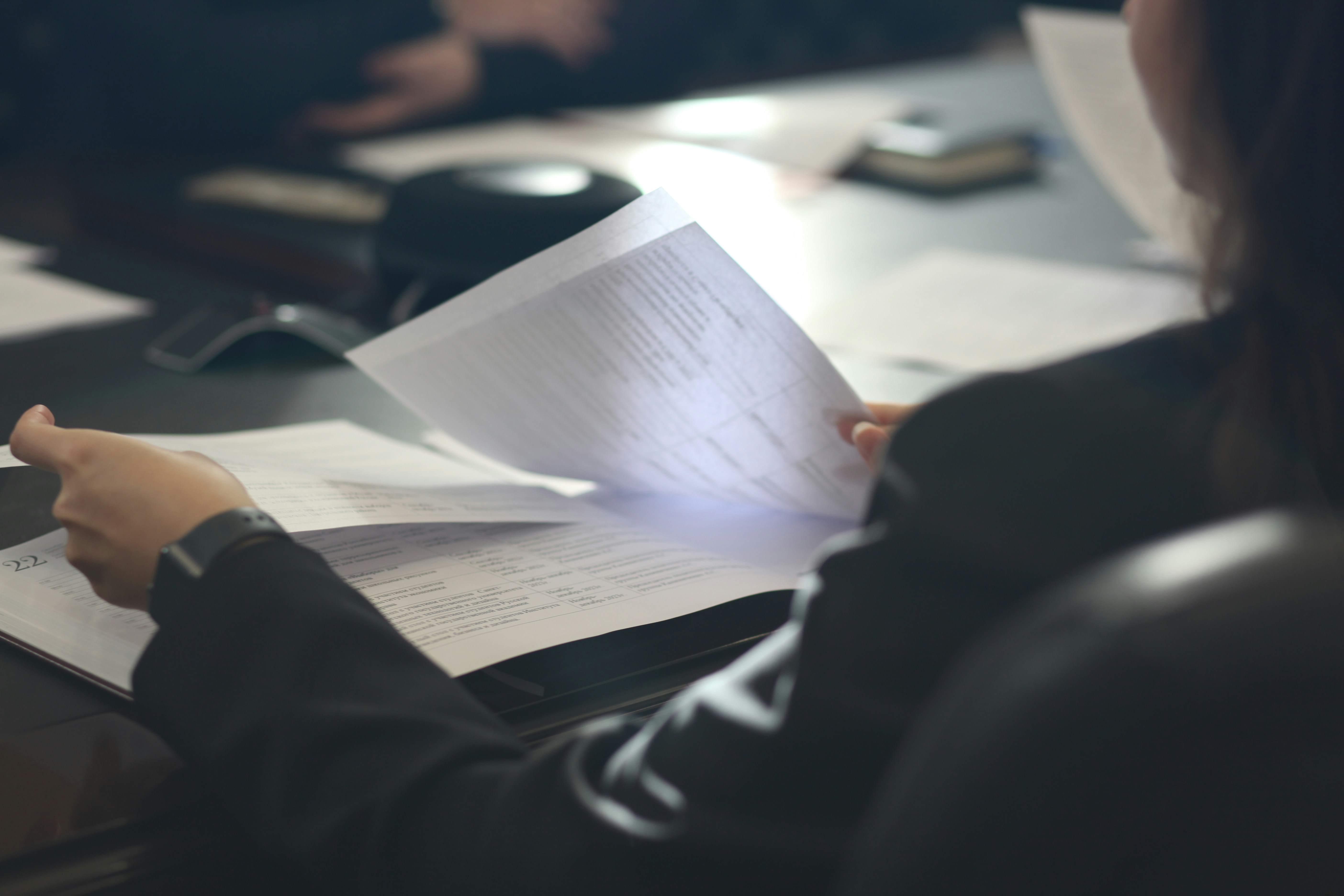 The picture describes a person sitting at a table and reviewing printed documents.