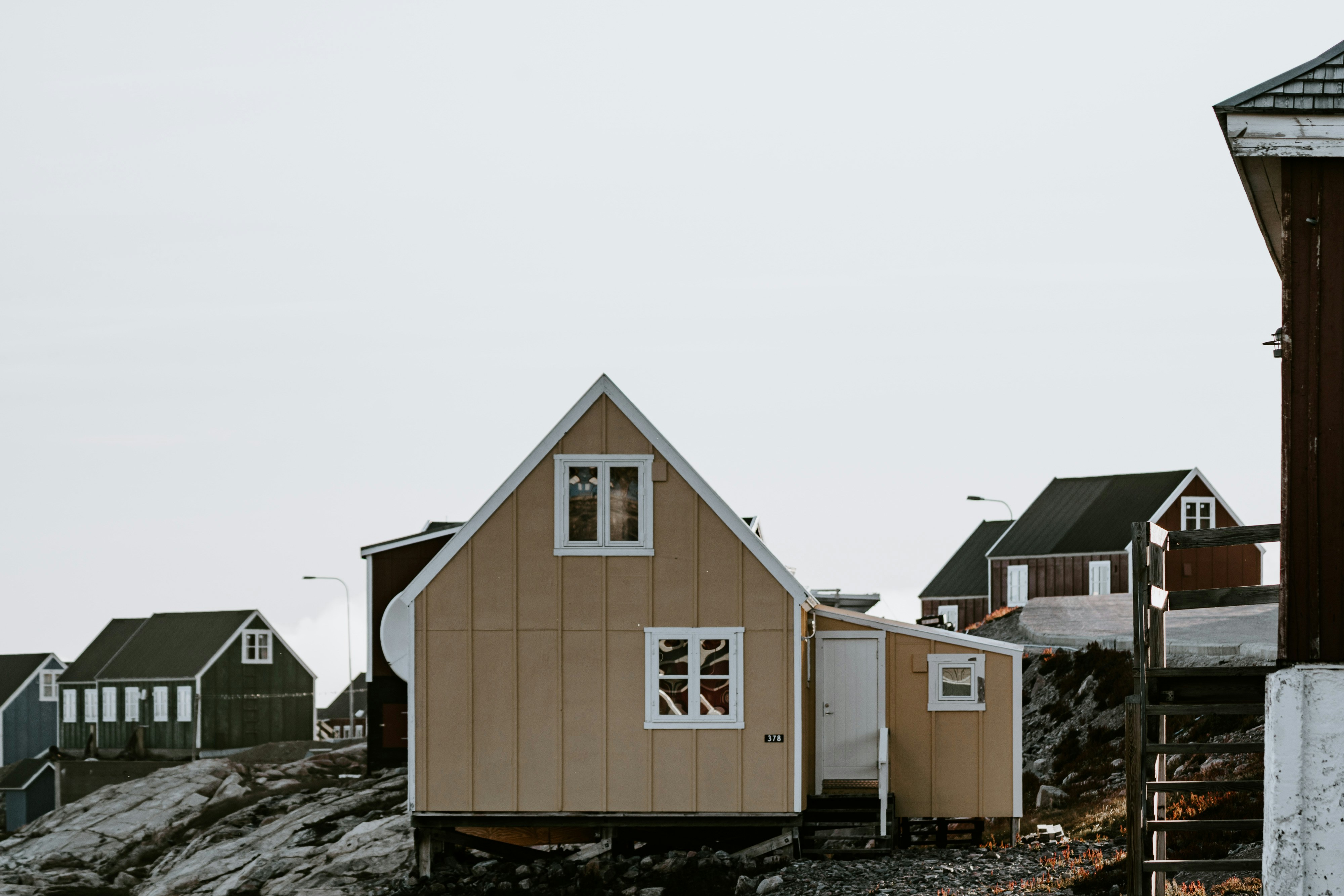 The image showcases a prefabricated house situated on rocky terrain in a remote settlement.