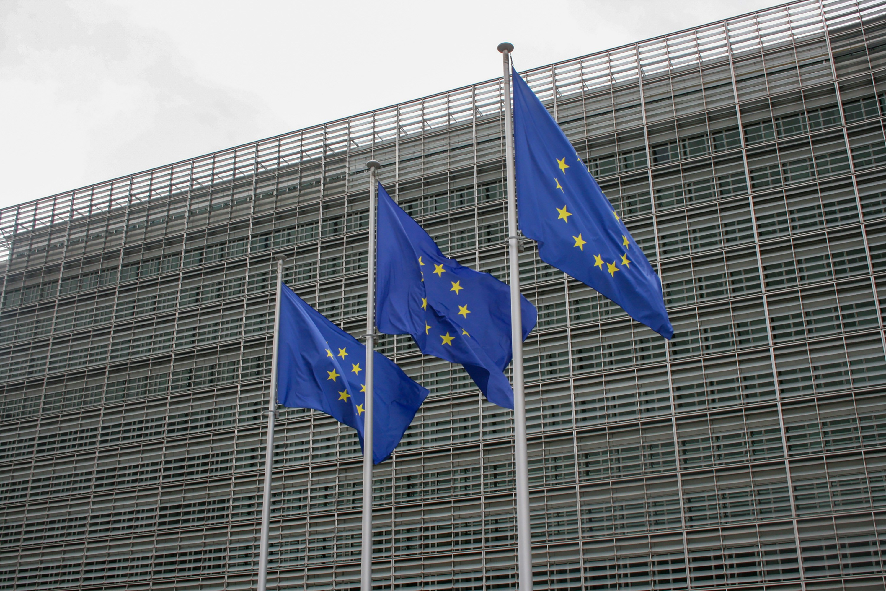 Three European flags flying in front of a building. 