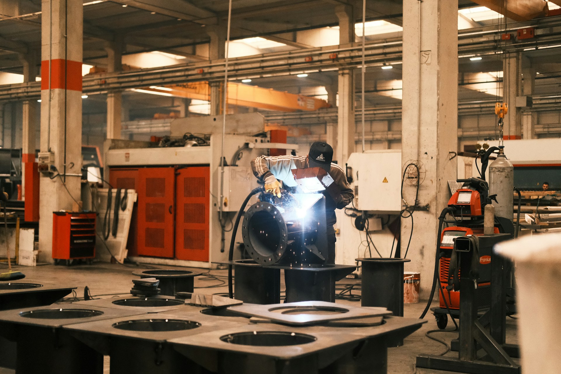 The photo presents a worker welding metal in a factory.