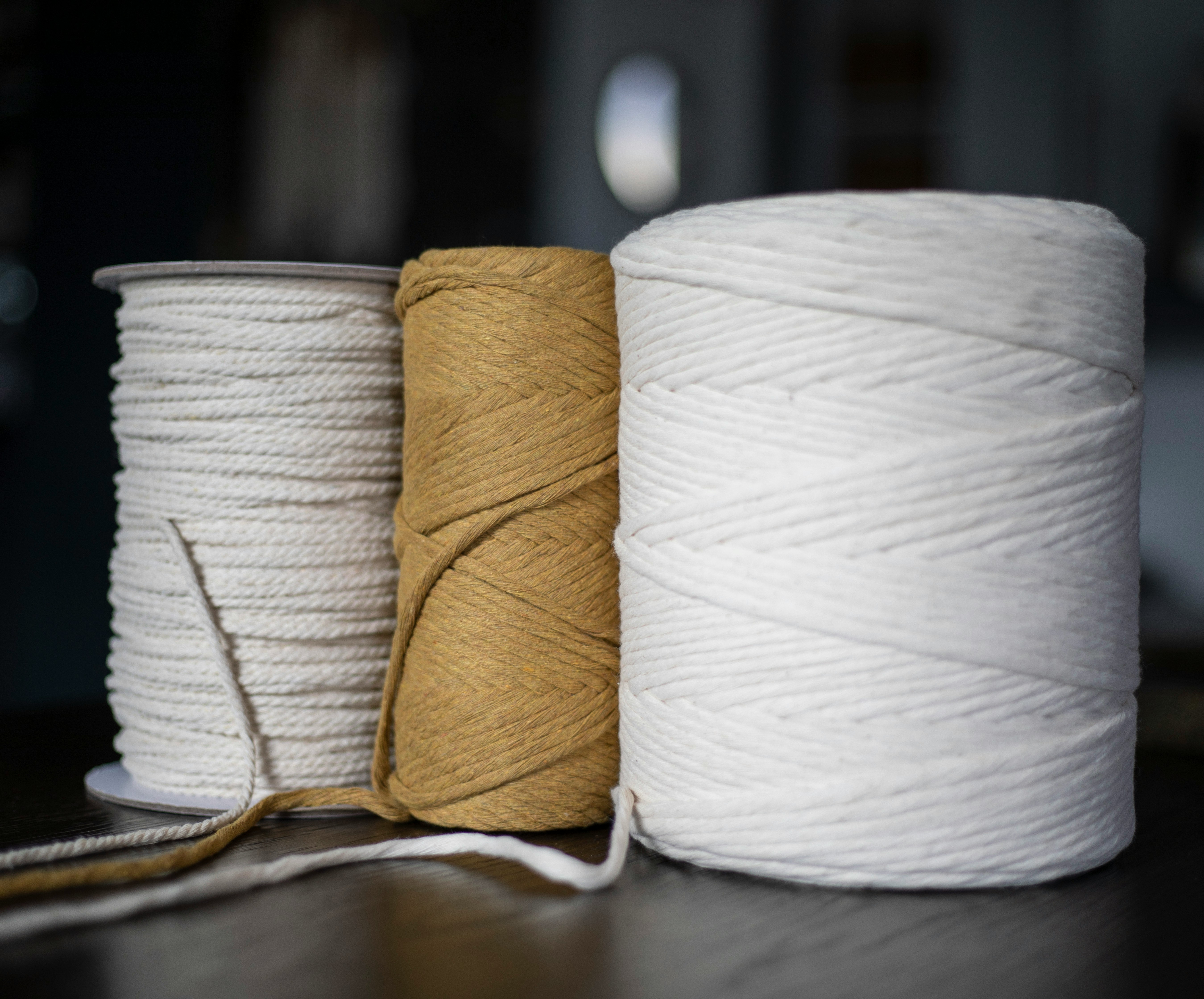 Three spools of twine are sitting on a table.