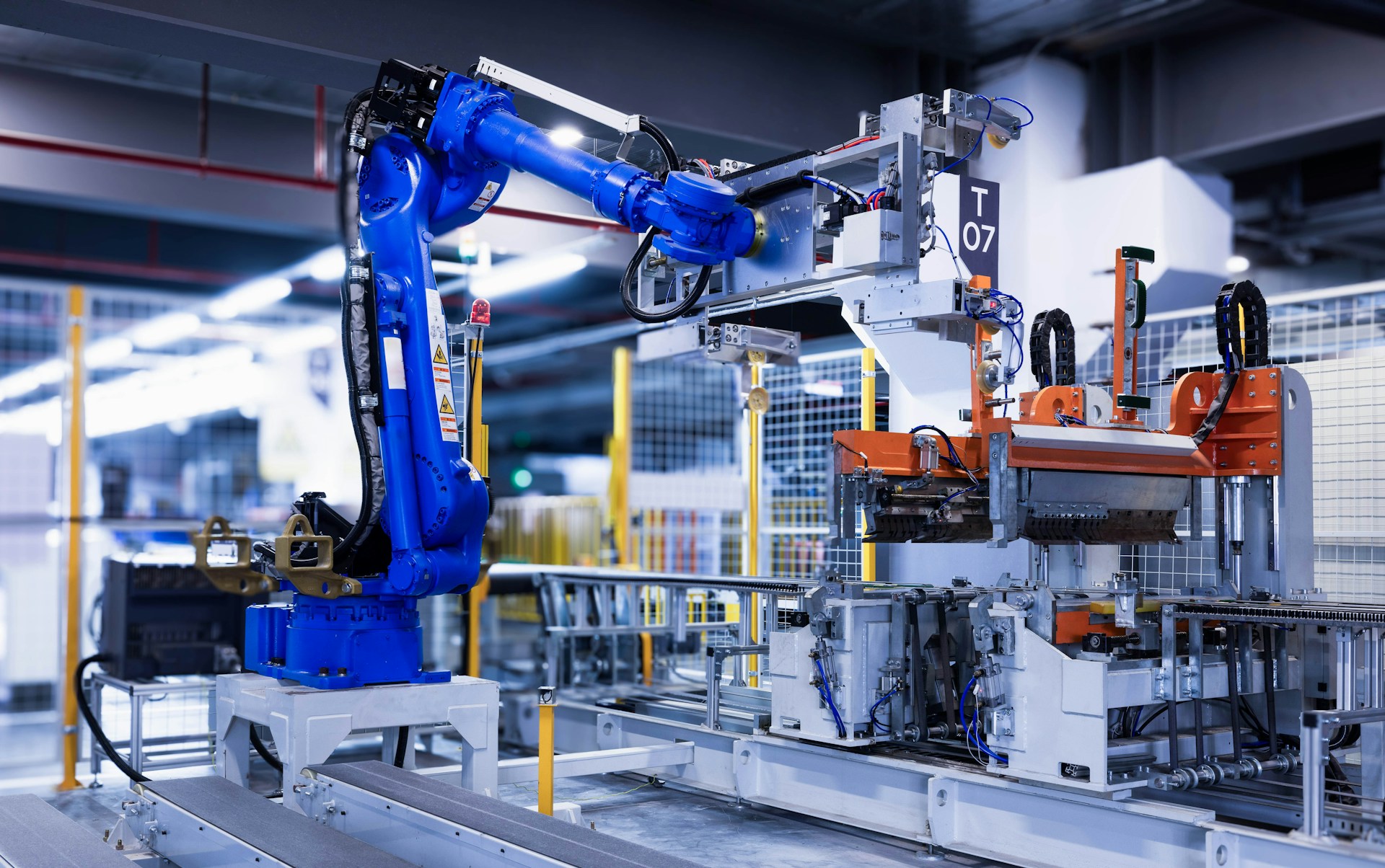 The photo presents an industrial robot working on a factory production line.