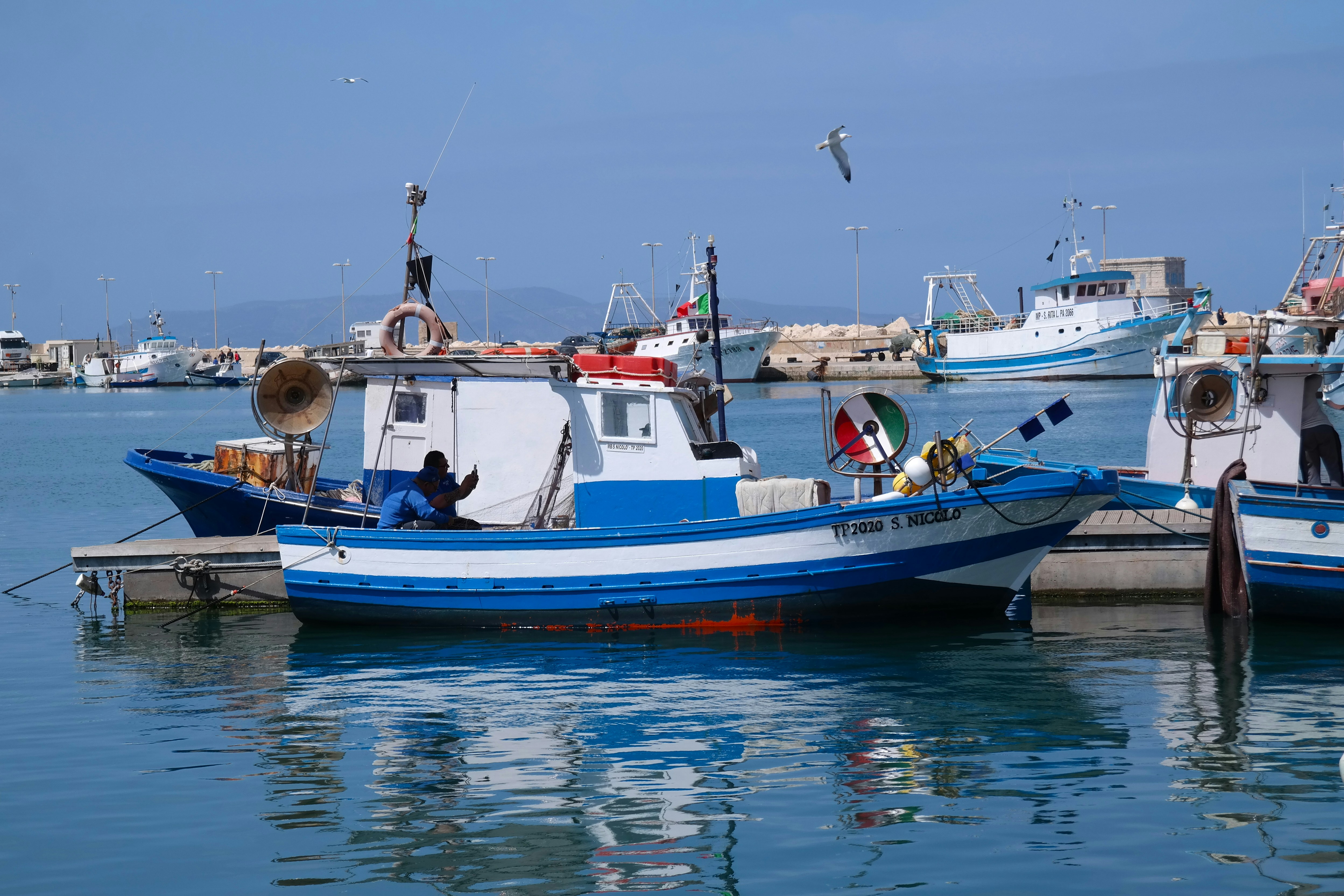 The photo presents Italian fishers at the harbor.