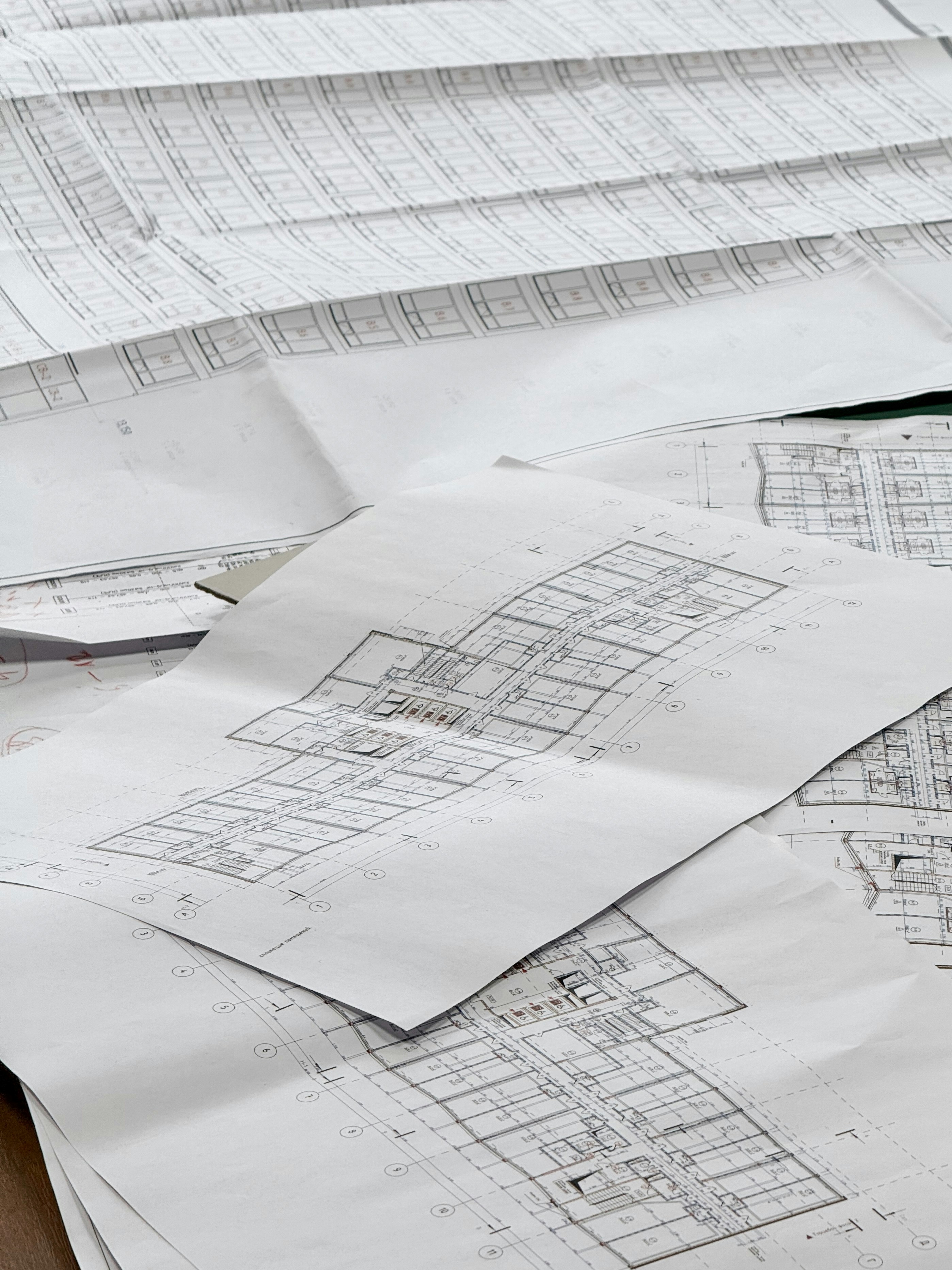 The picture shows several large architectural and engineering floor plans spread across a table