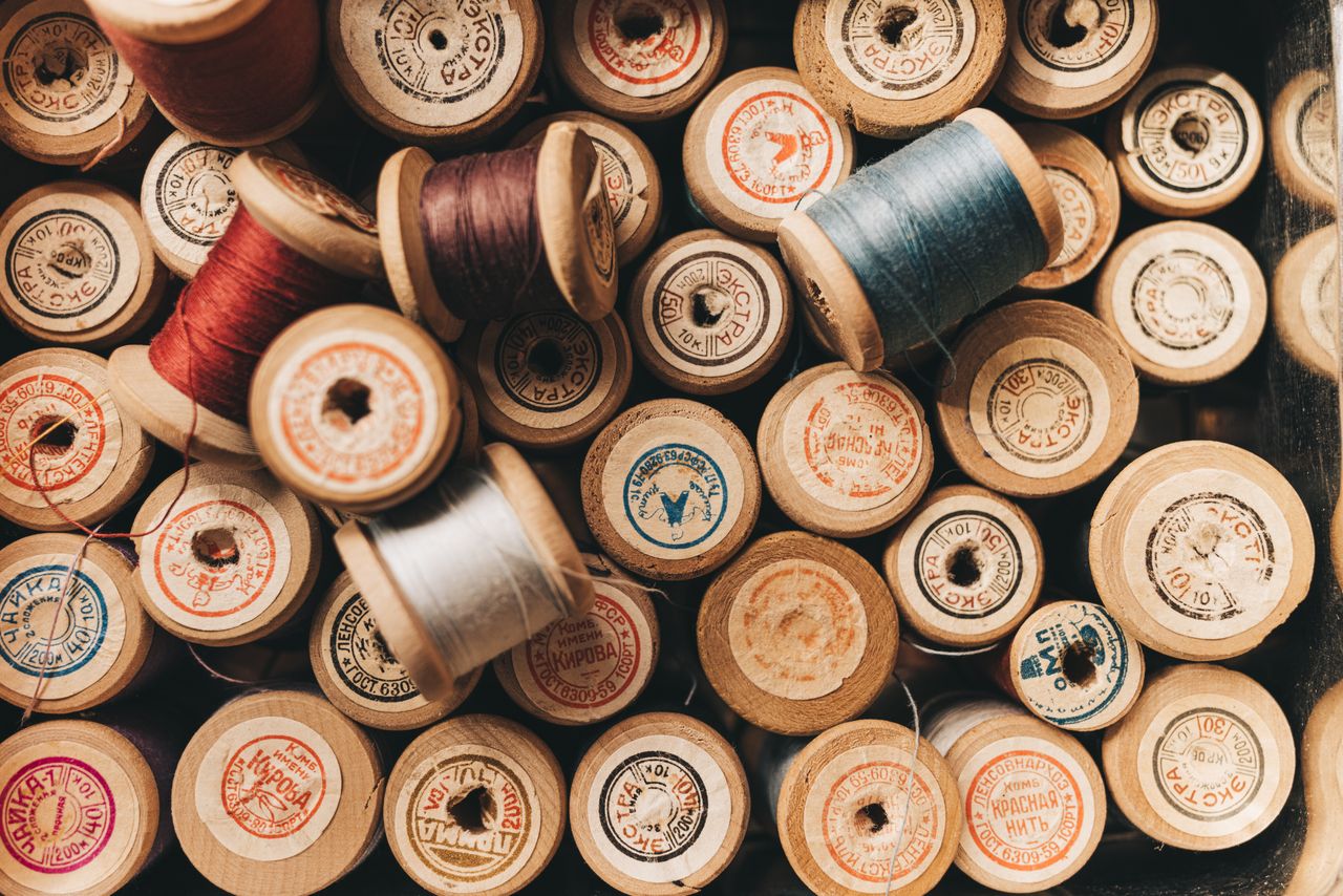 A collection of vintage wooden thread spools with colourful threads.